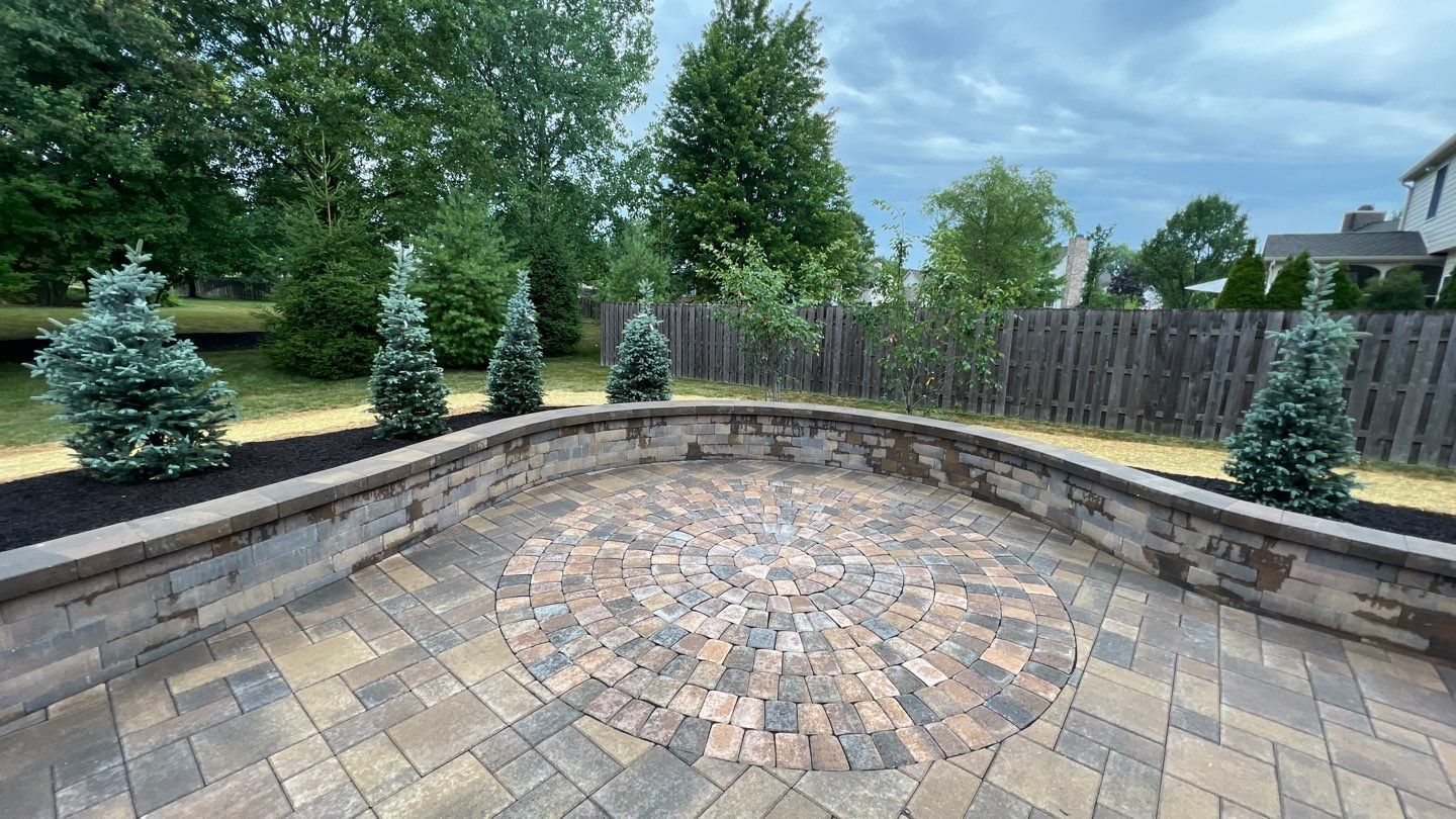 There is a brick patio with a circular design in the middle of it.