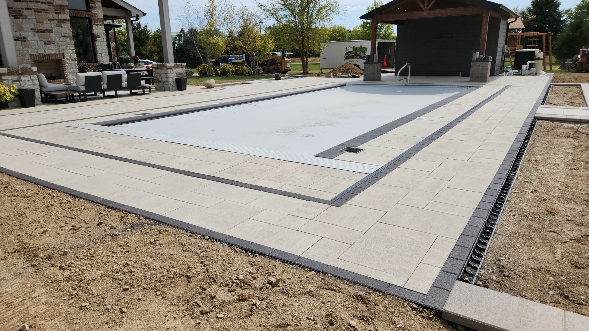 A large swimming pool is being built in the backyard of a house.