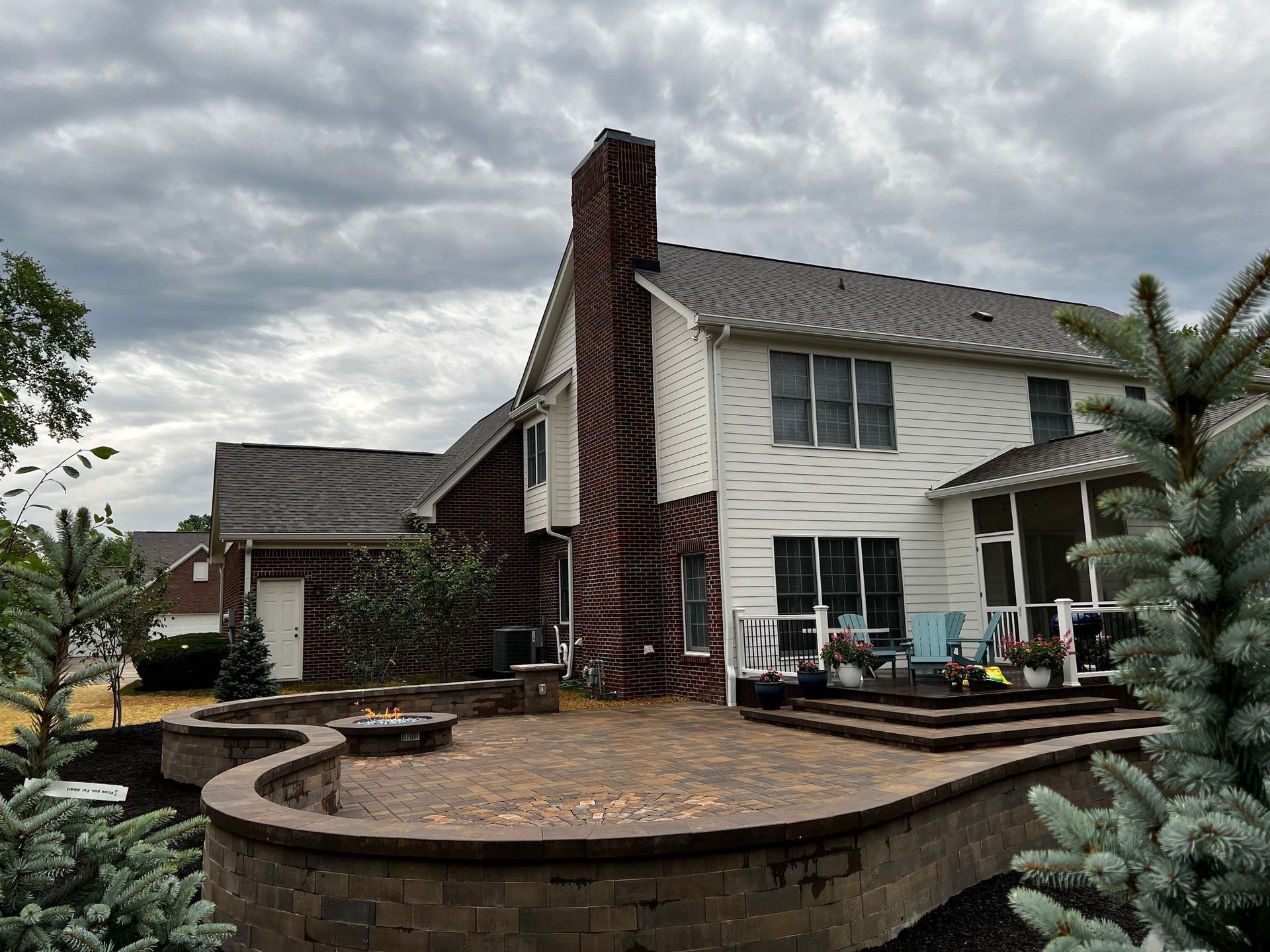 A large white house with a brick chimney and a patio in front of it.
