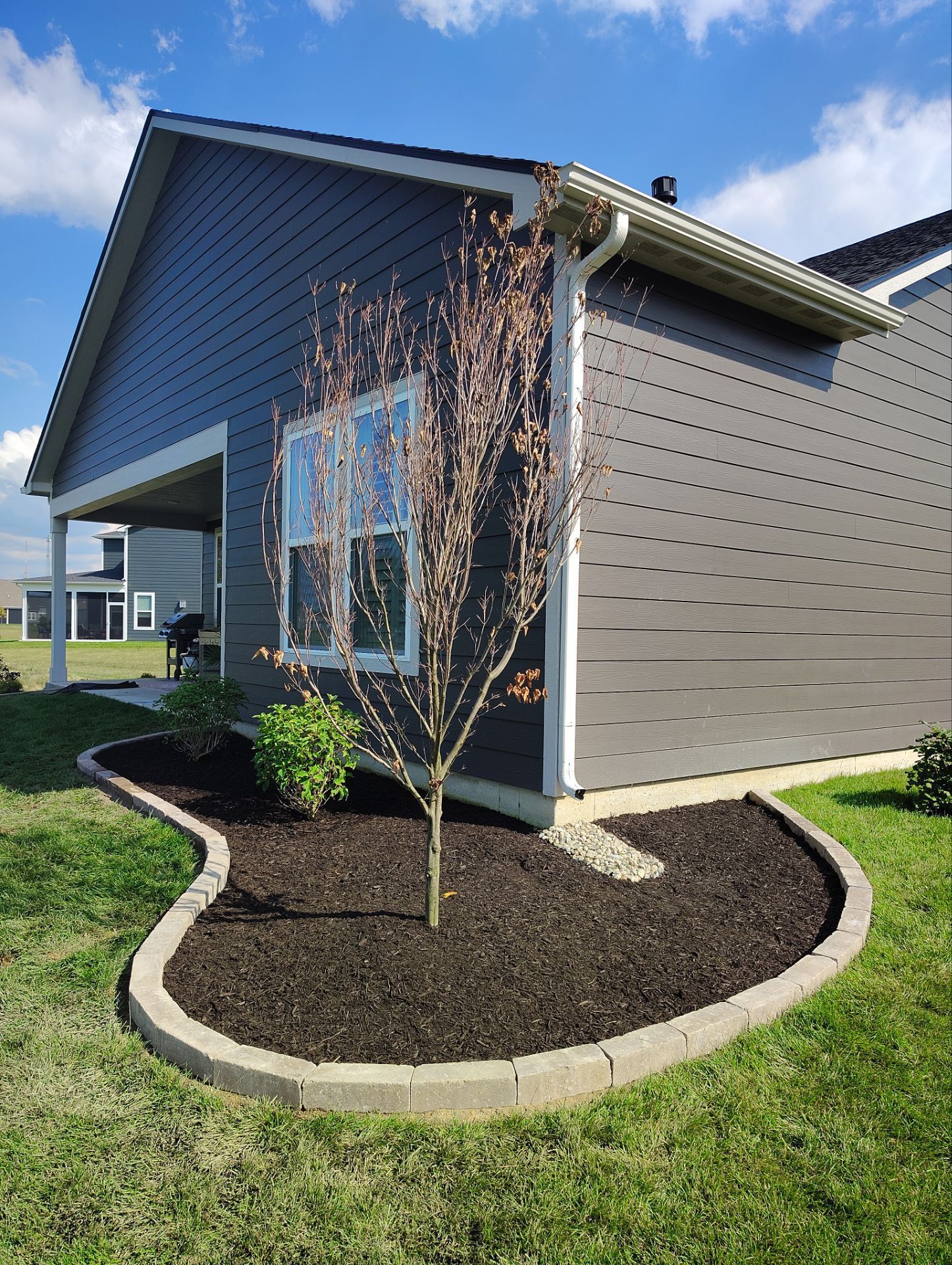 A gray house with a tree in front of it.