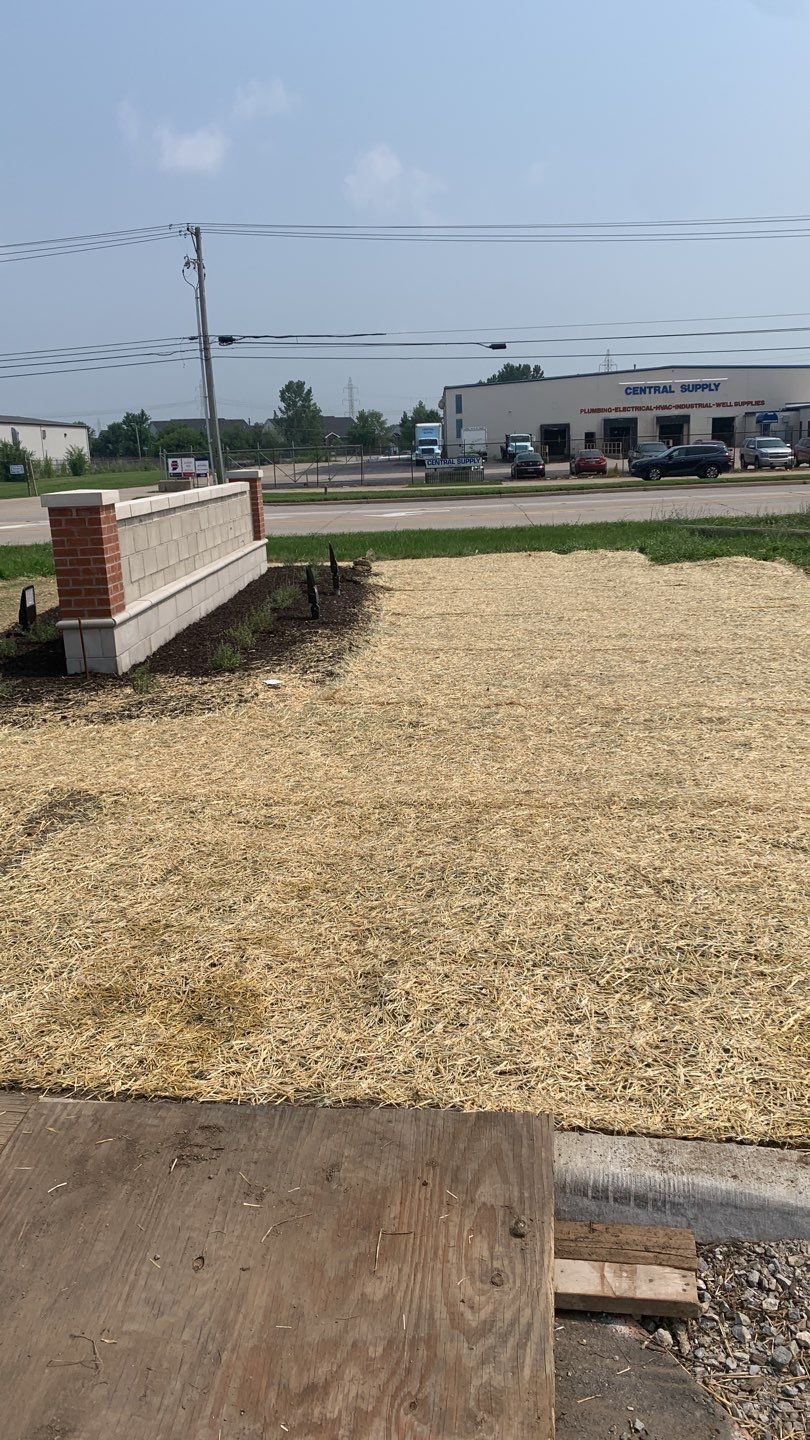 A pile of wood chips is sitting on the ground in front of a building.