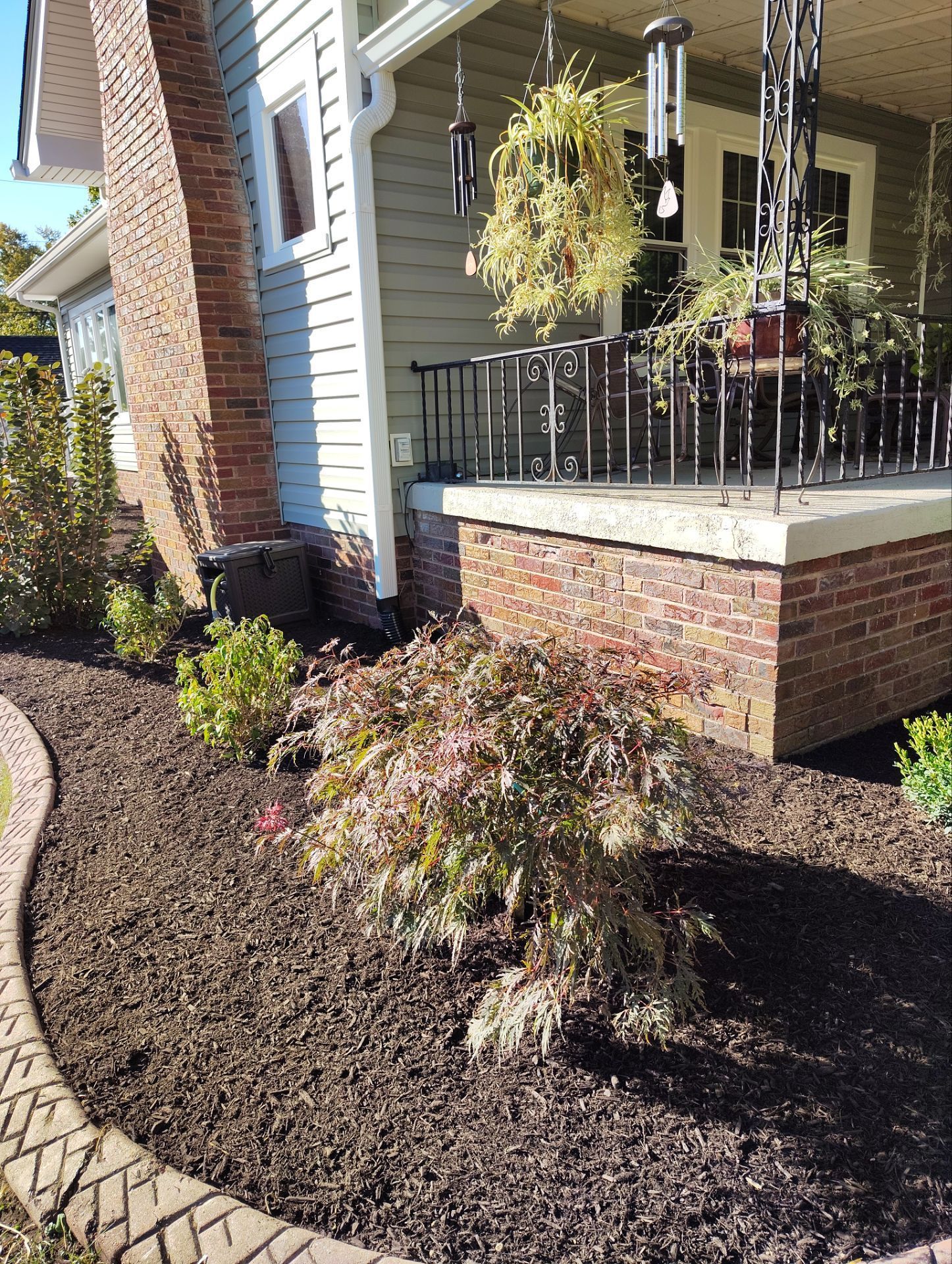 A house with a porch and a lot of plants in front of it.