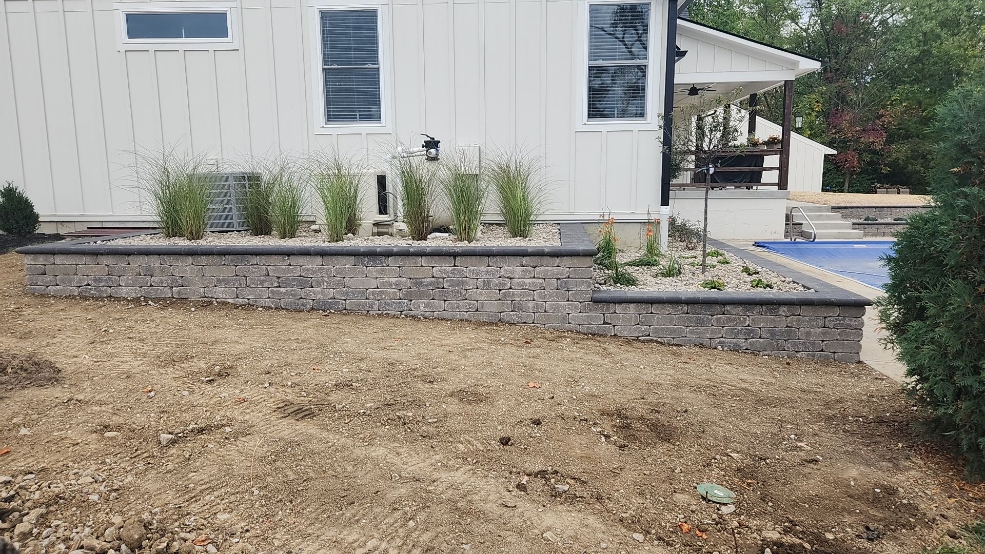 A white house with a stone wall in front of it.