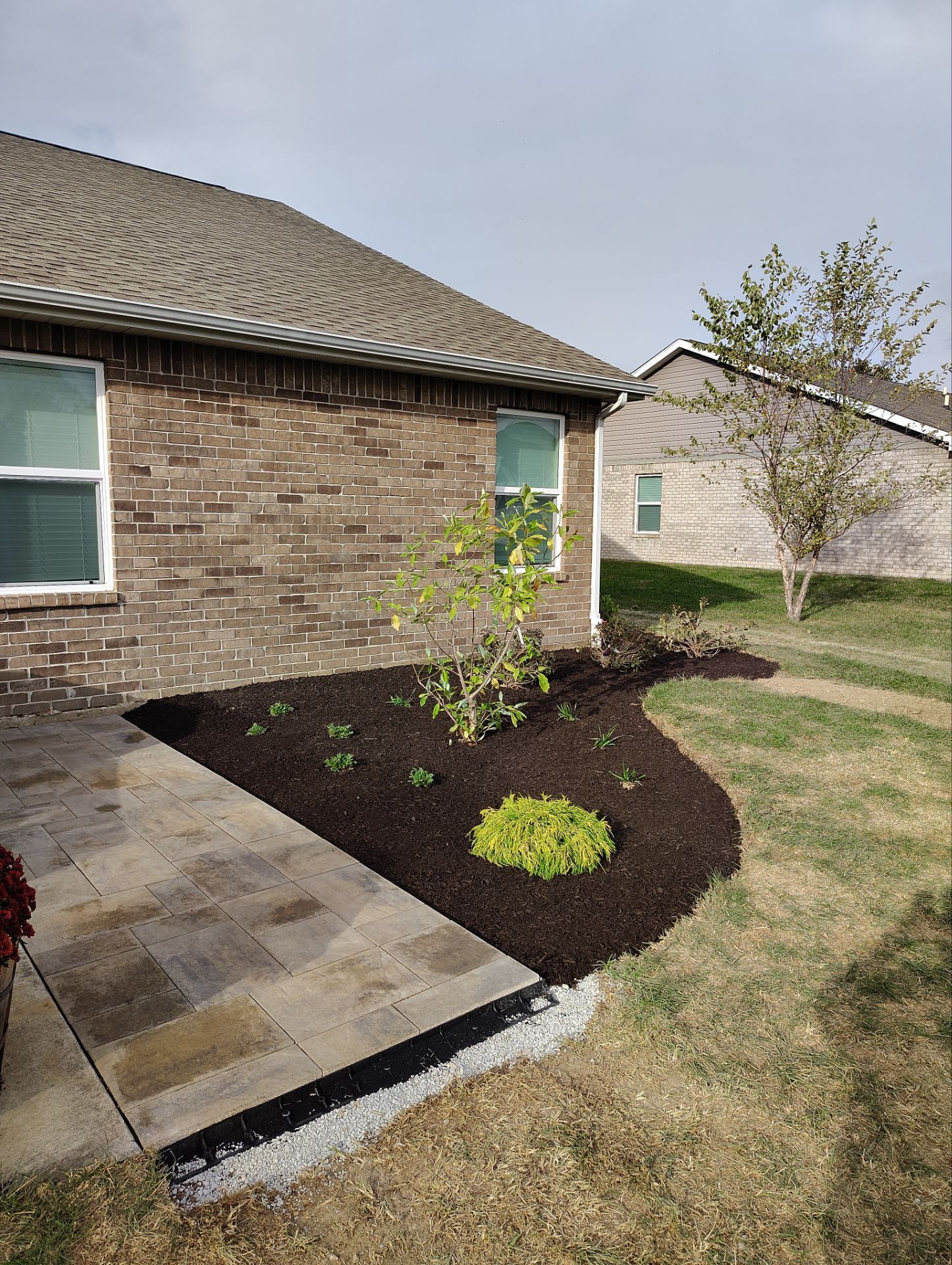 A brick house with a walkway leading to it and a garden in front of it.