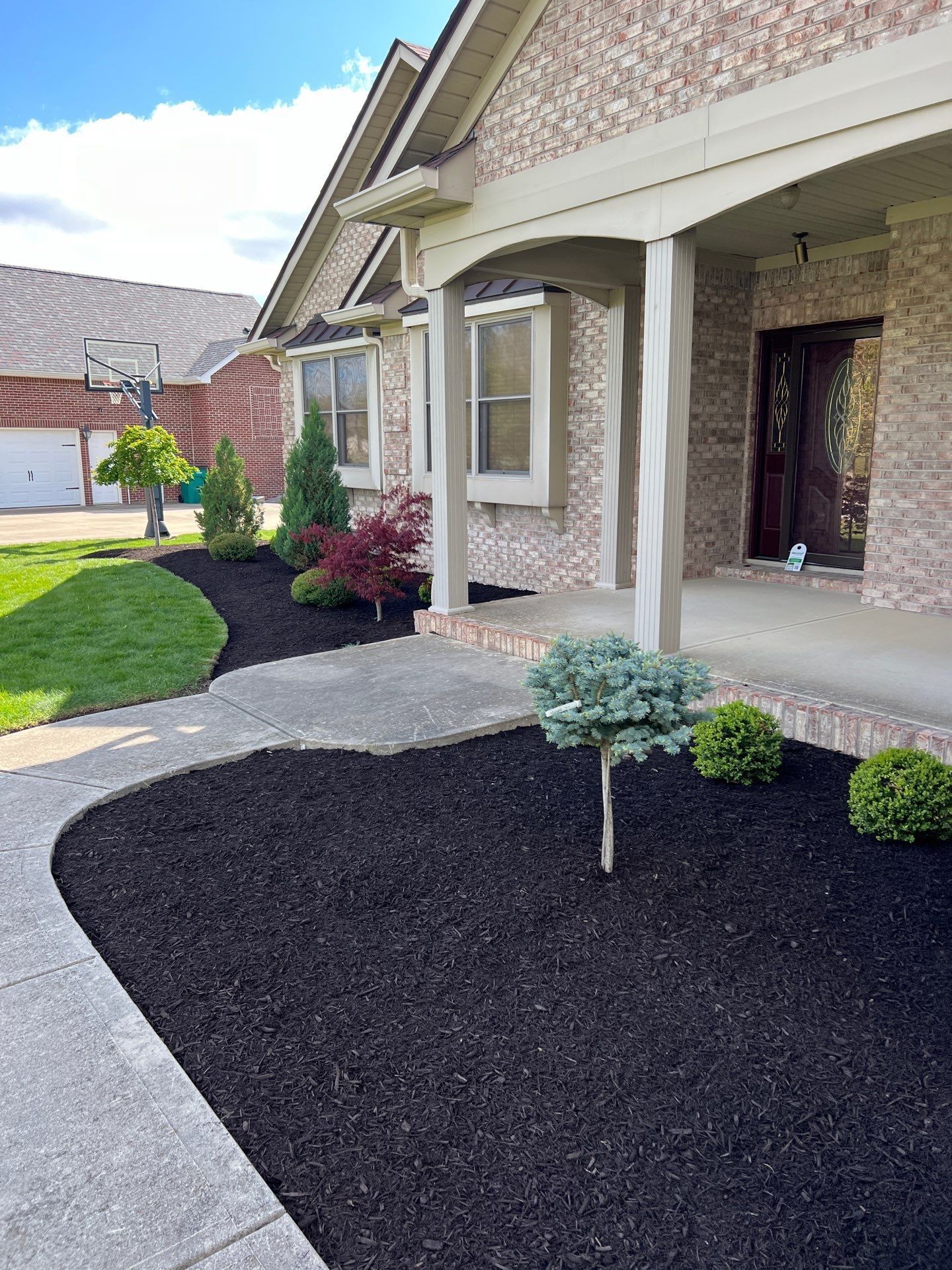 A brick house with a walkway and a tree in front of it.