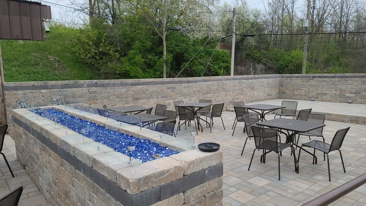 A patio with tables and chairs and a fire pit.