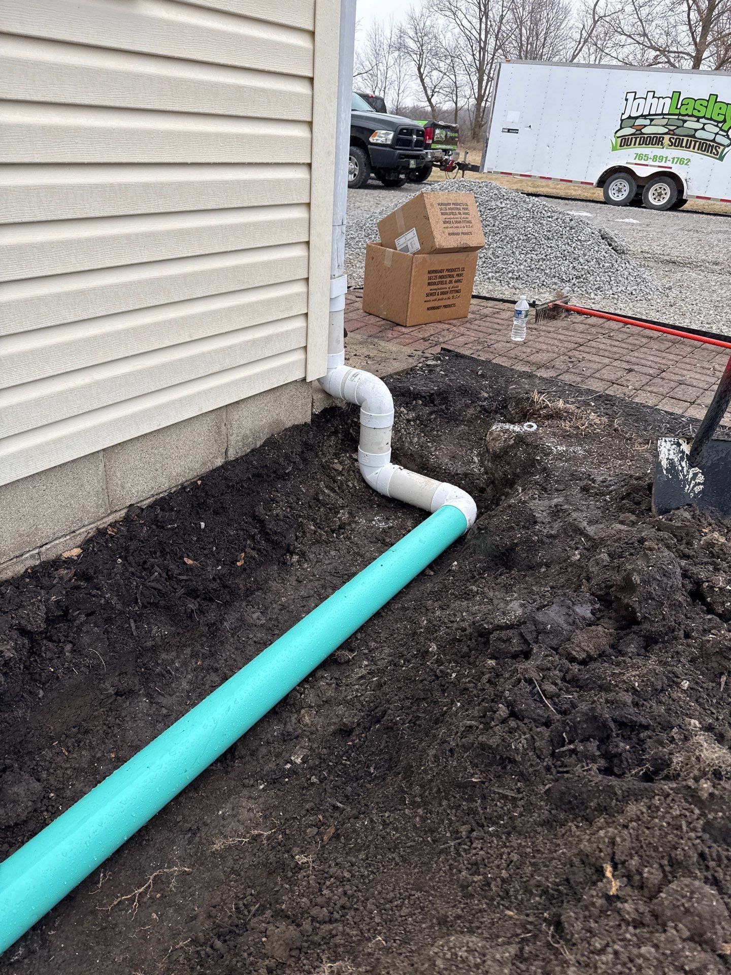 A green pipe is being installed on the side of a house.