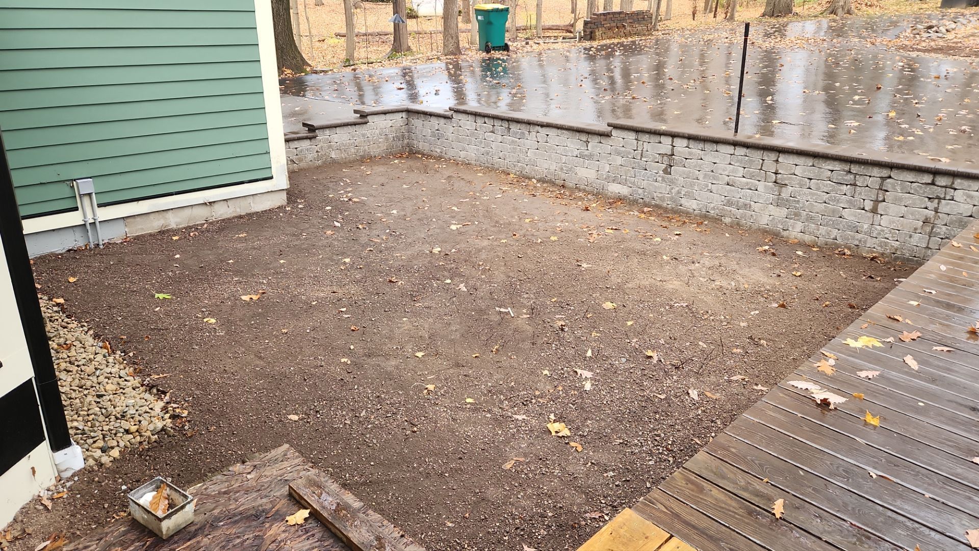 A patio with a wooden deck and a brick wall in the background.