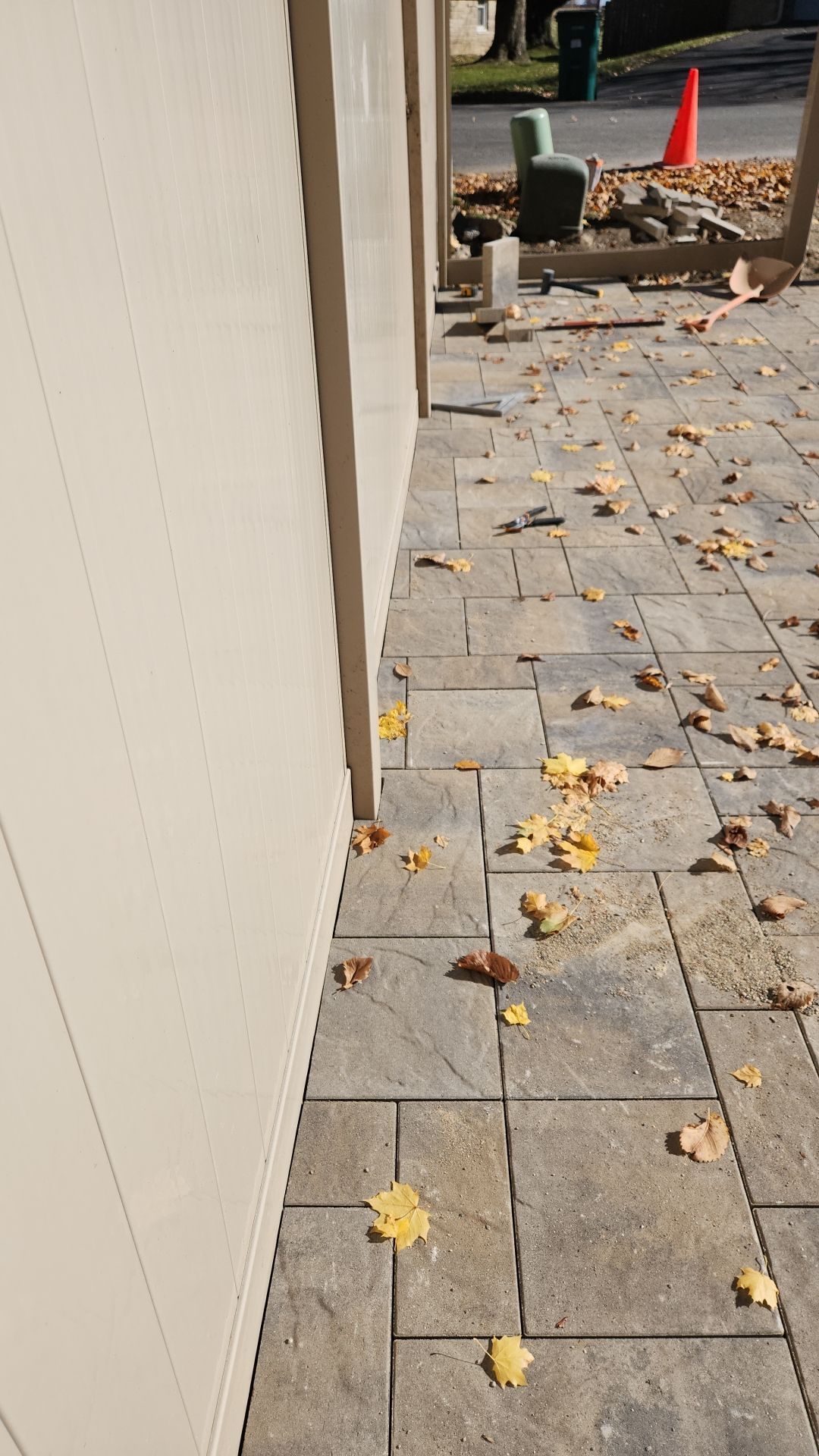 A sidewalk with leaves on it is being built next to a building.