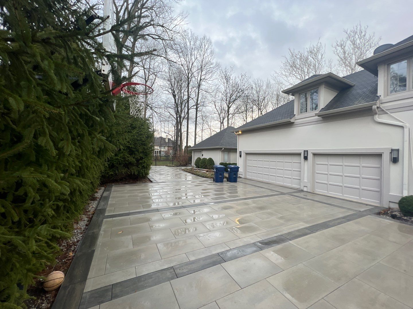 A driveway leading to a house with a basketball hoop in the background.