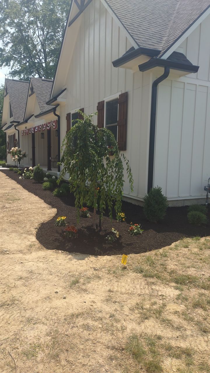 A white house with a black gutter and a driveway leading to it.