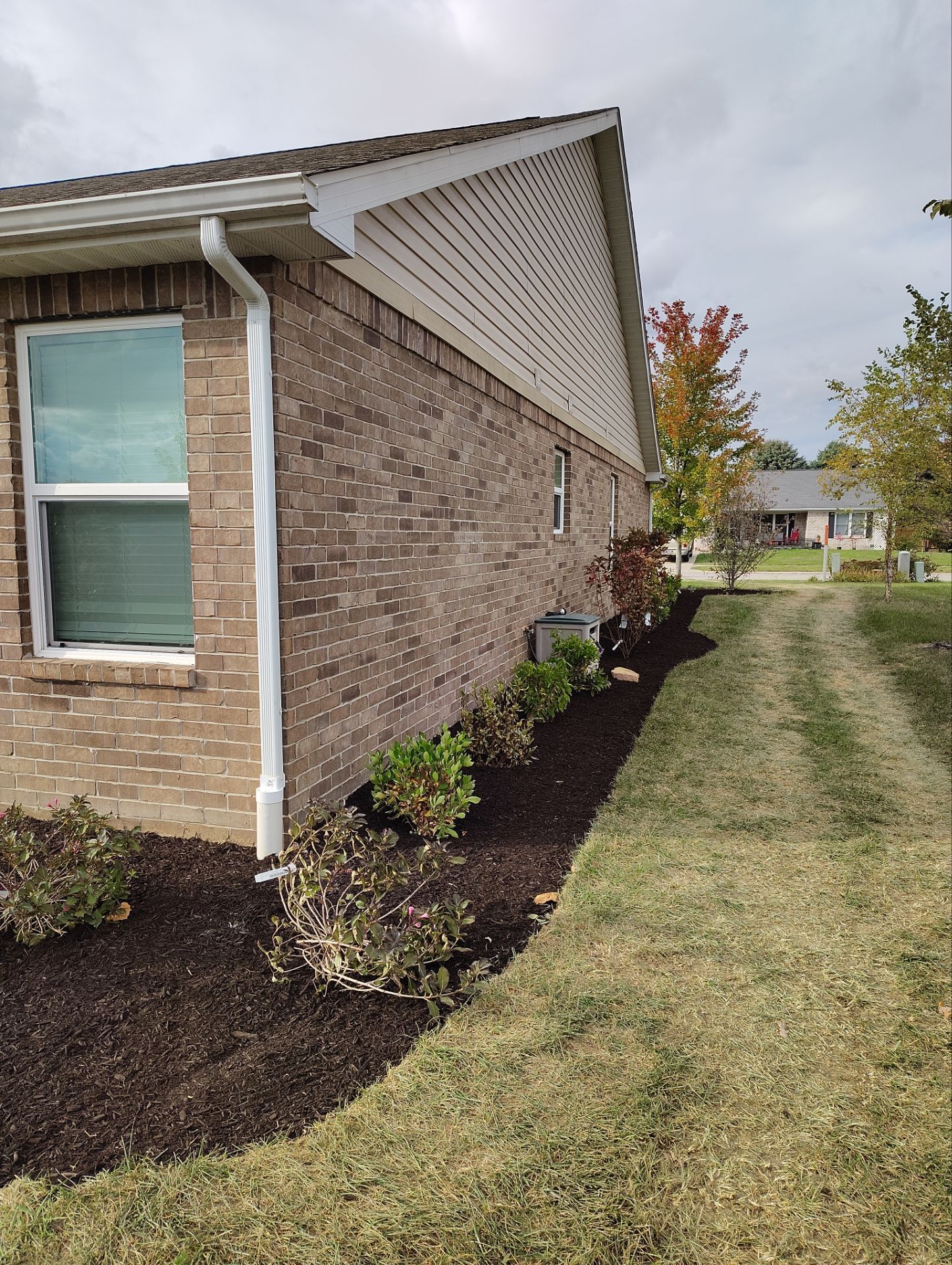 A brick house with a lush green lawn in front of it.