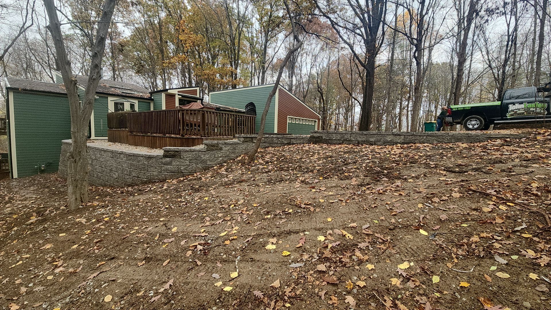 A truck is parked in front of a house in the woods.