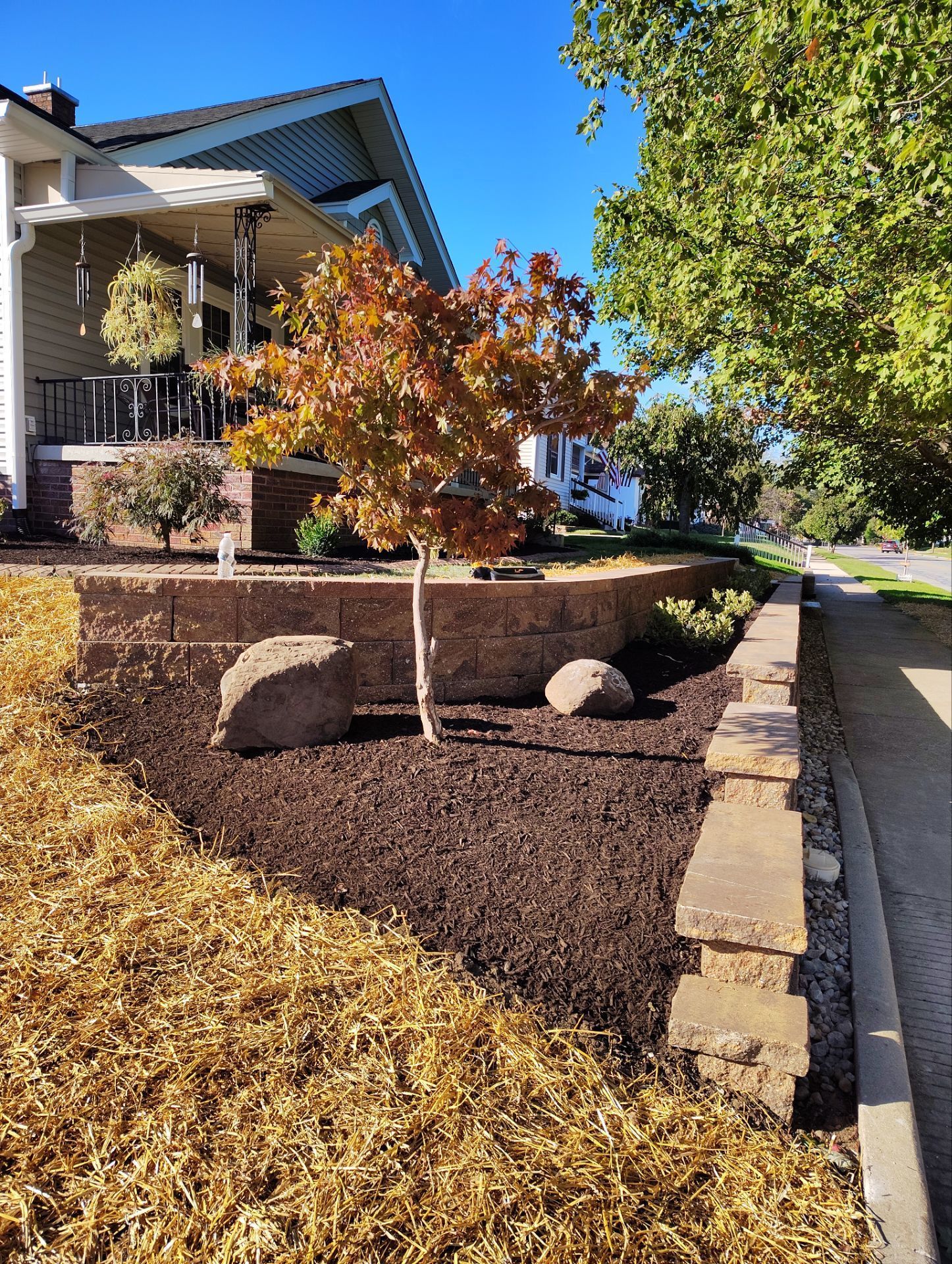 A house with a brick wall and a tree in front of it.