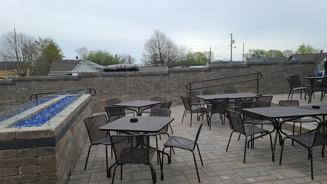 A patio with tables and chairs and a fire pit.