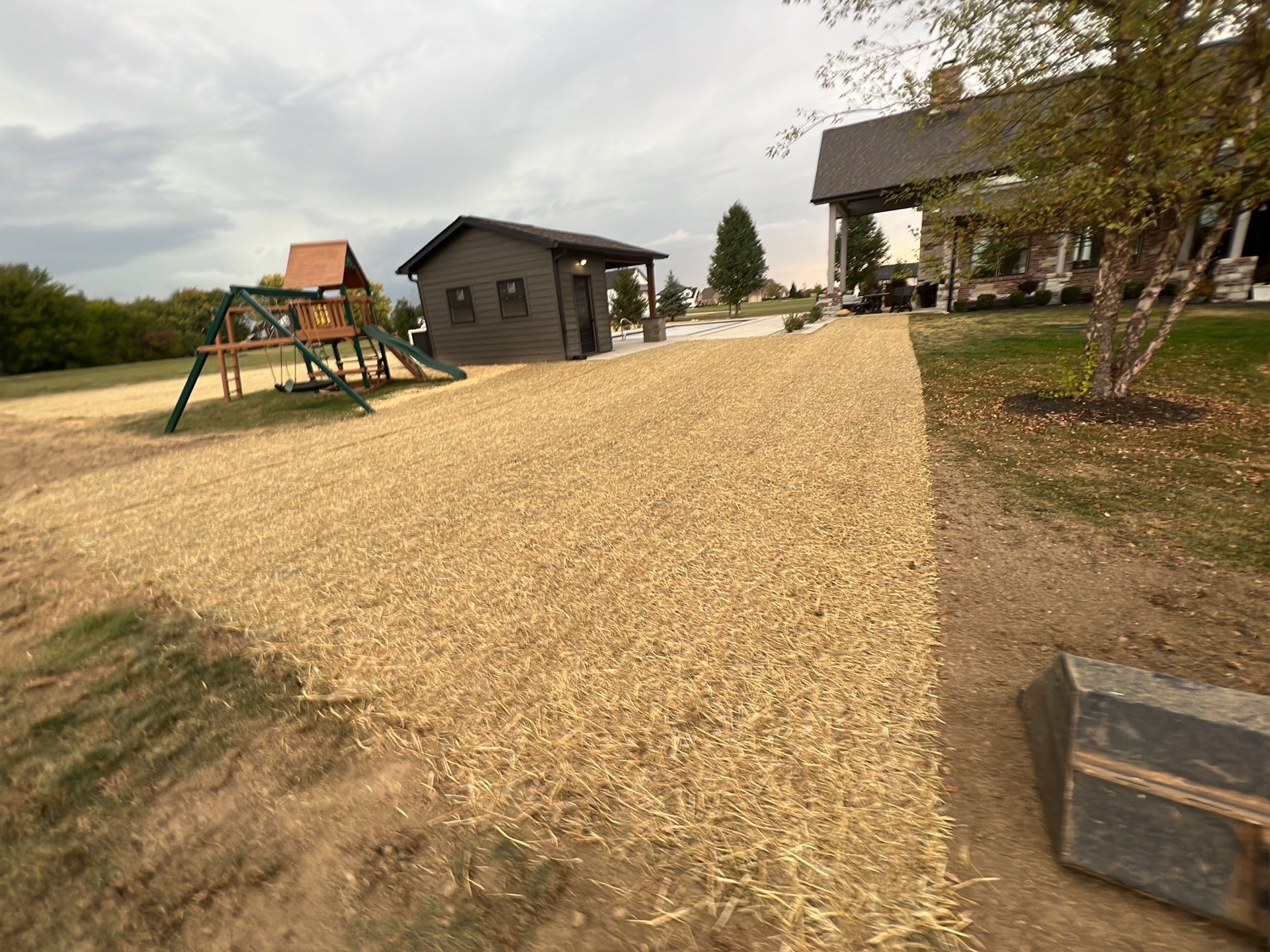A playground with a swing set and a house in the background.