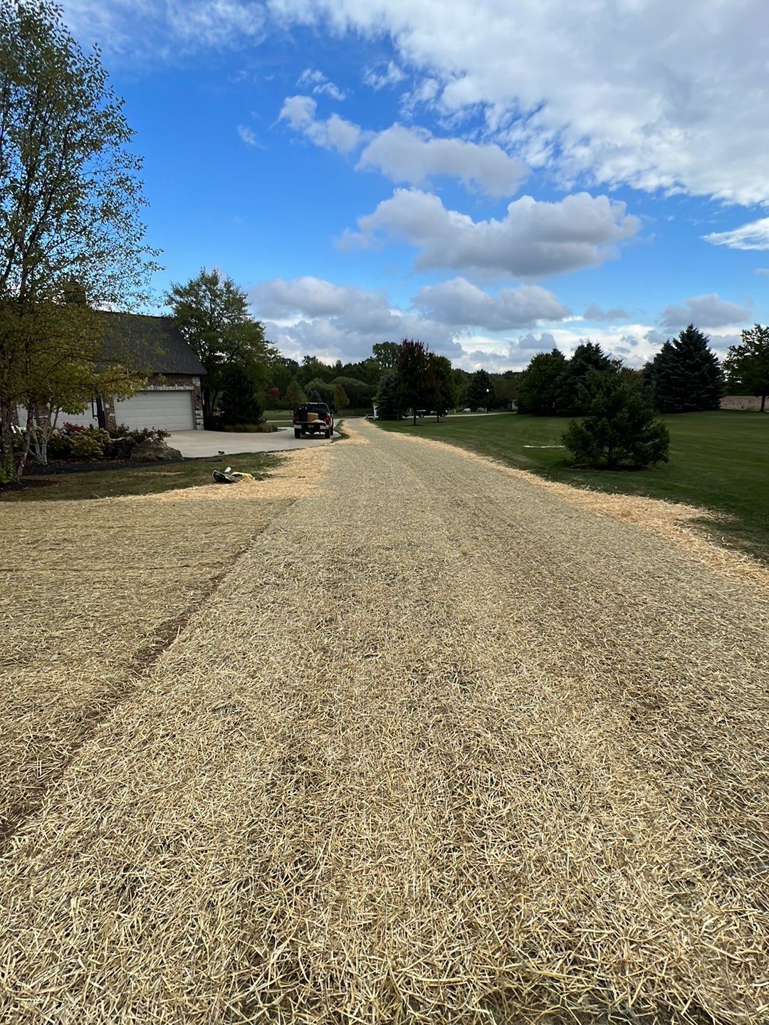 A gravel driveway leading to a house on a sunny day.