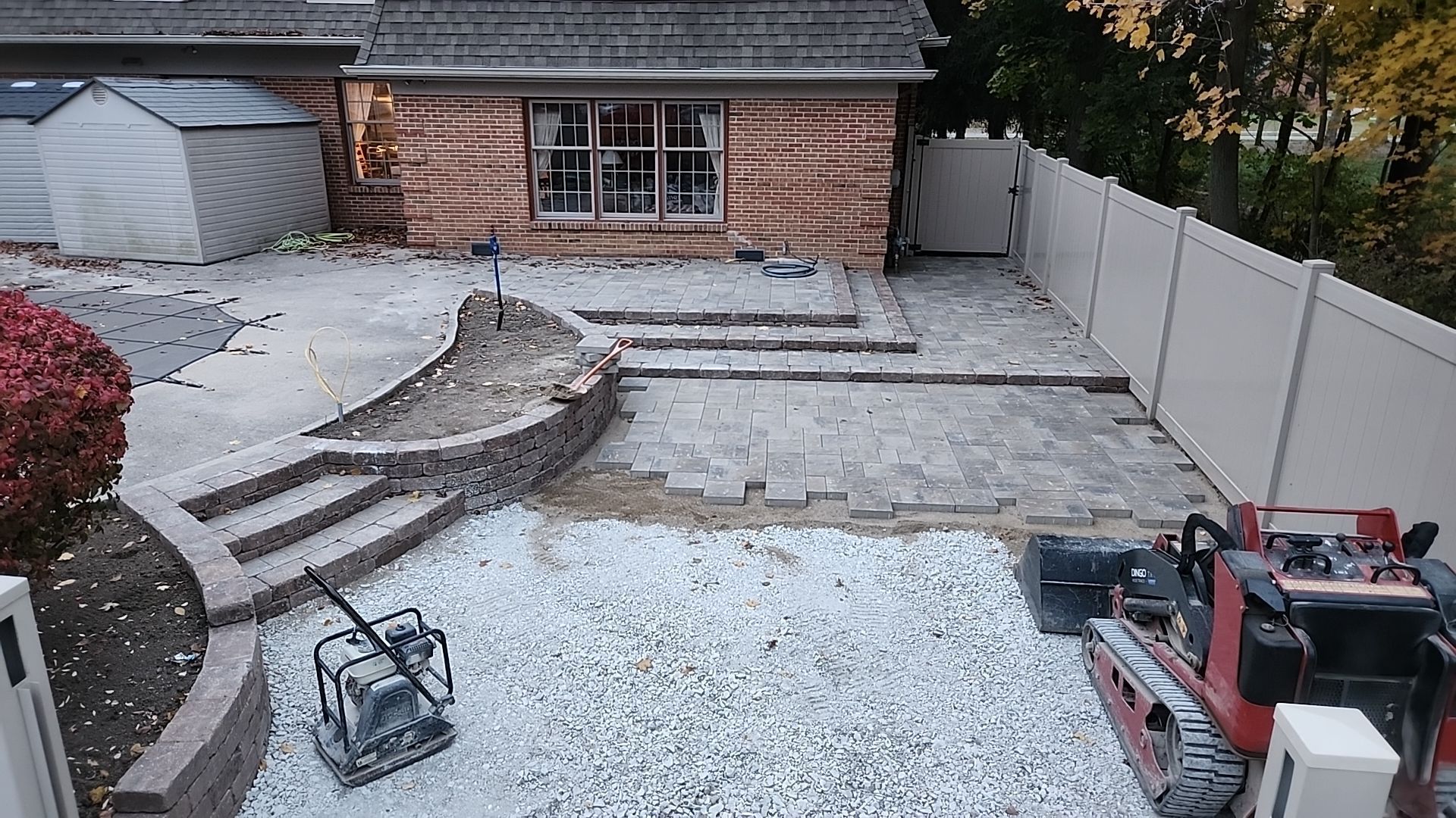 A brick house is being built with a gravel driveway in front of it