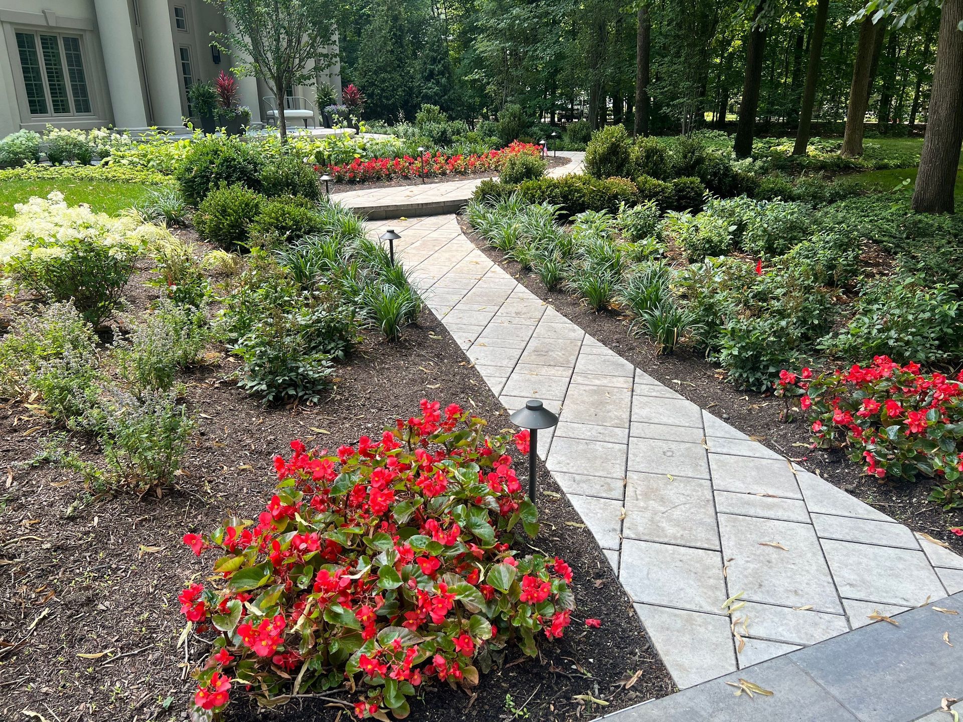 A walkway surrounded by flowers and bushes in a garden.