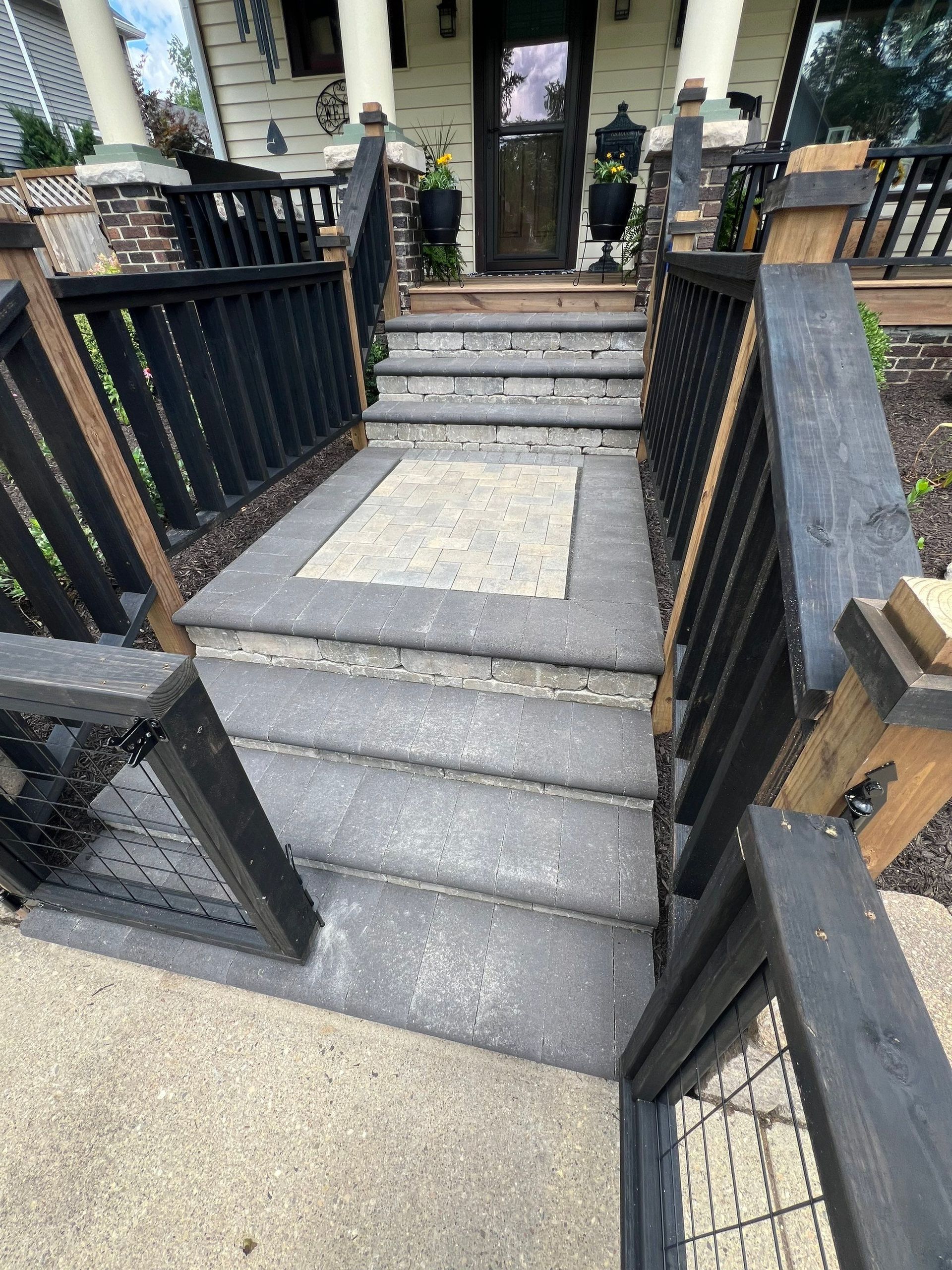 A set of stairs leading up to a house with a black railing.