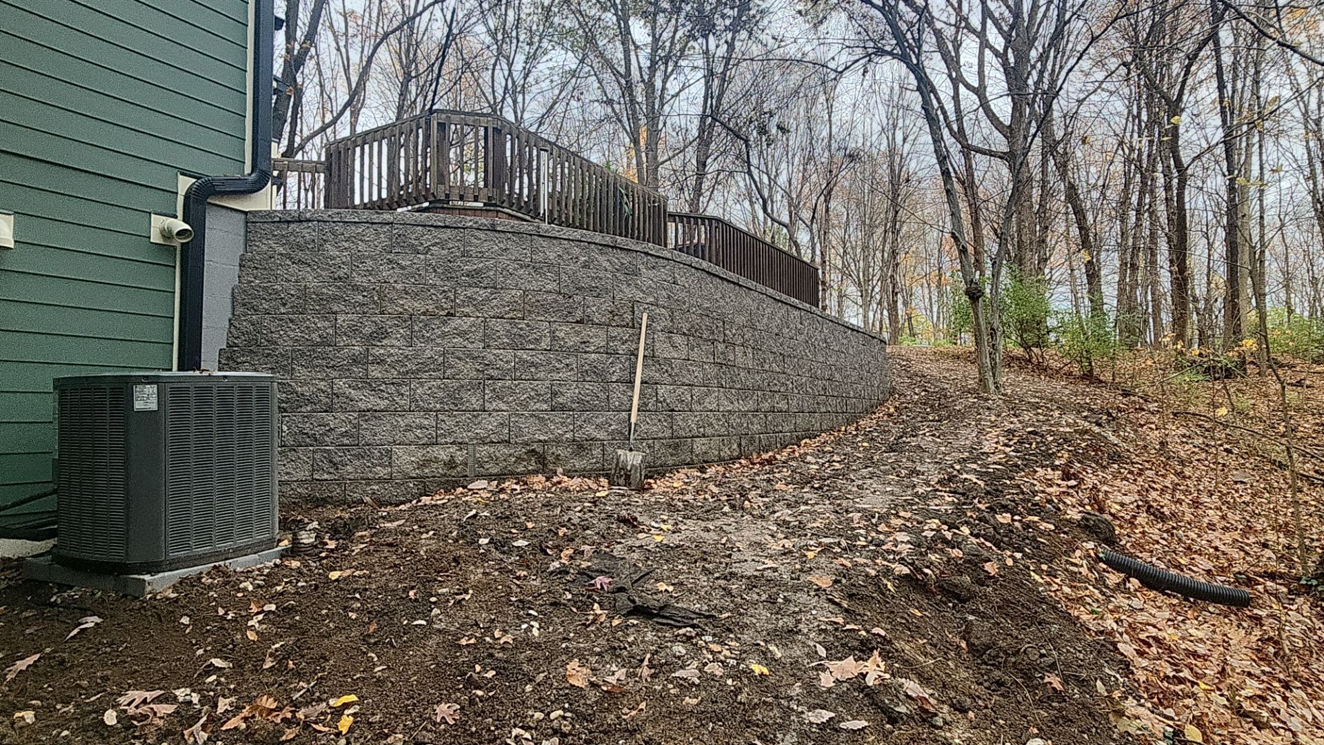 There is a brick wall in the backyard of a house surrounded by trees.
