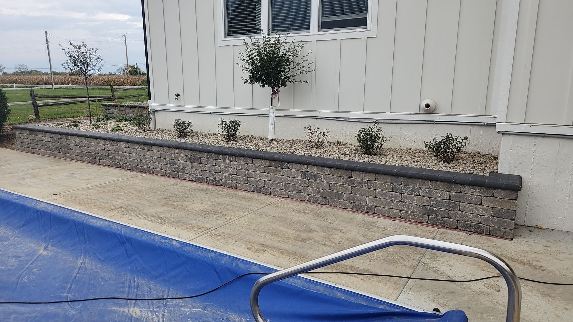 A swimming pool with a blue cover and a white house in the background.
