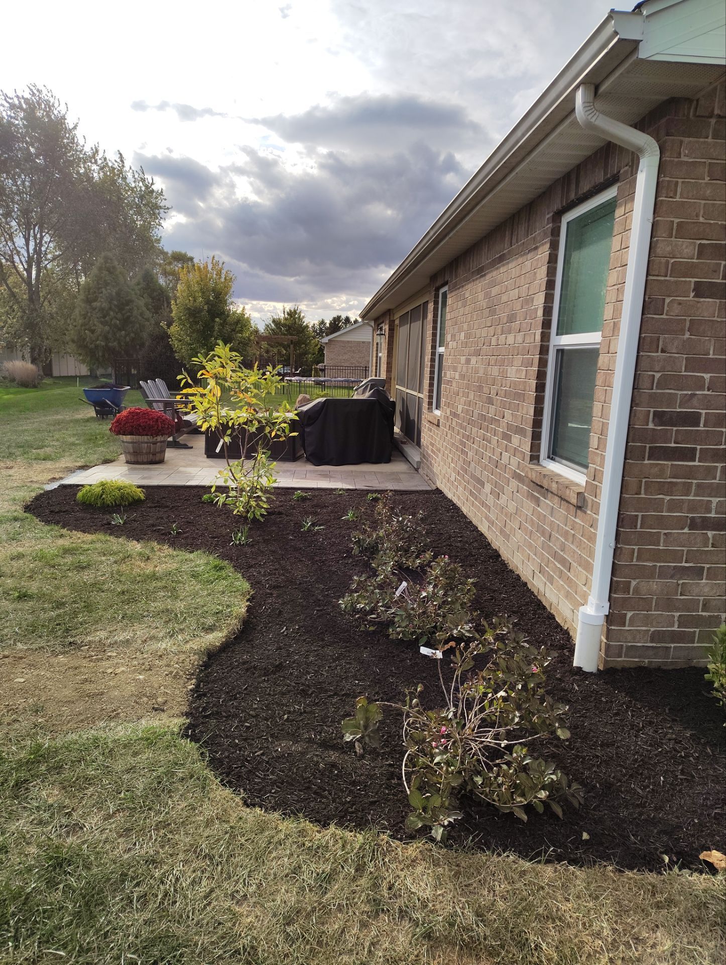 A brick house with a patio and a drainpipe on the side of it.