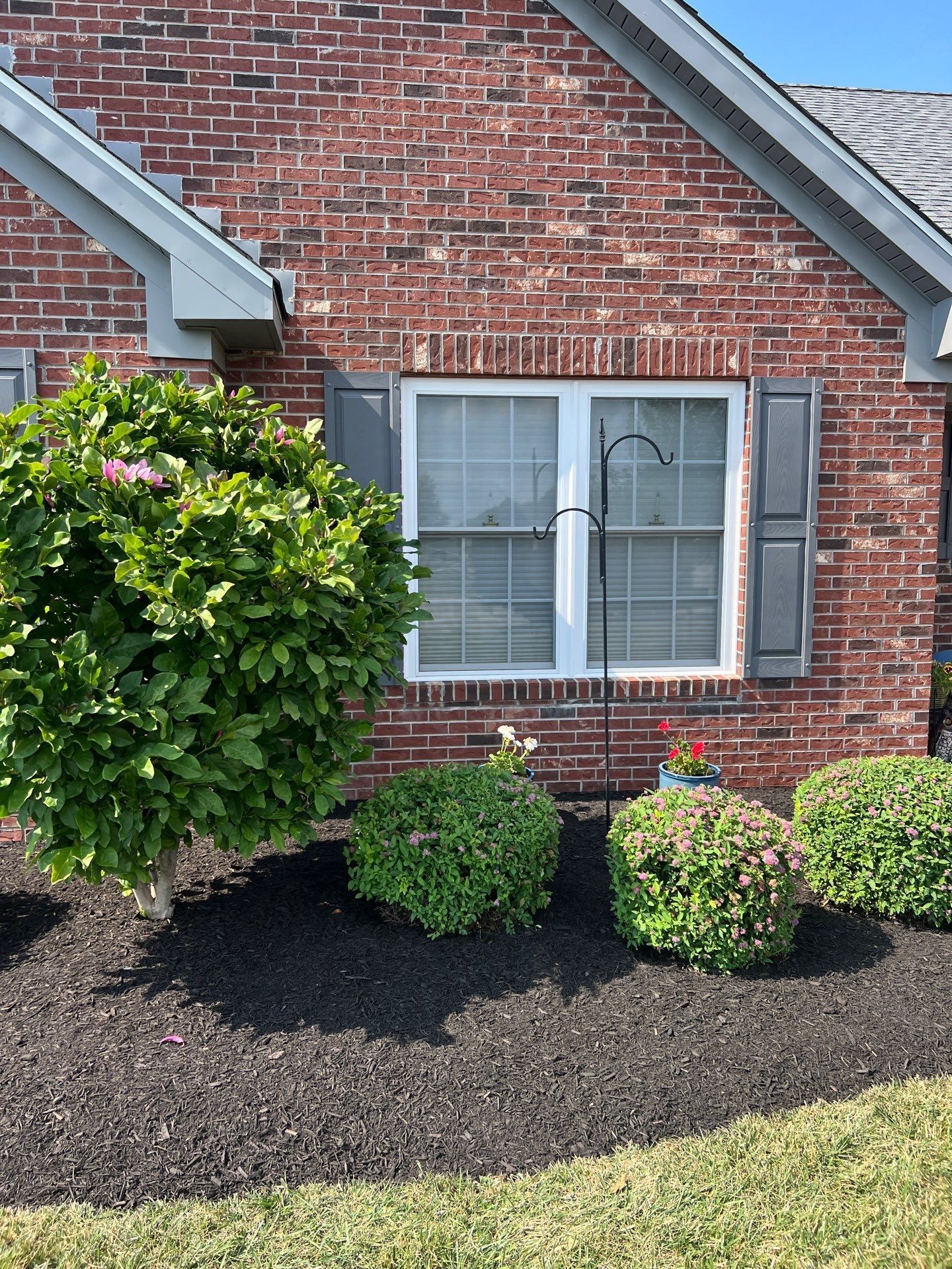 A brick house with a white window and shutters