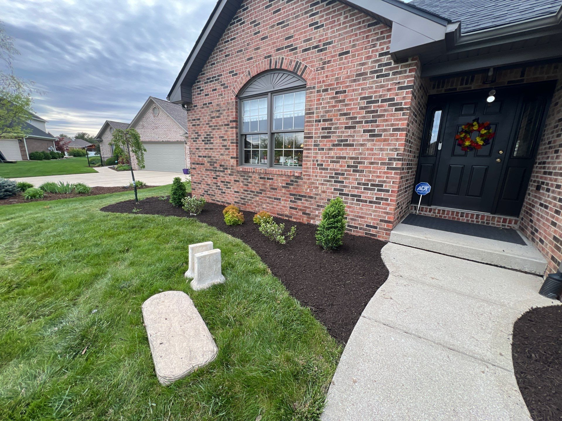 A brick house with a black door and a walkway leading to it.