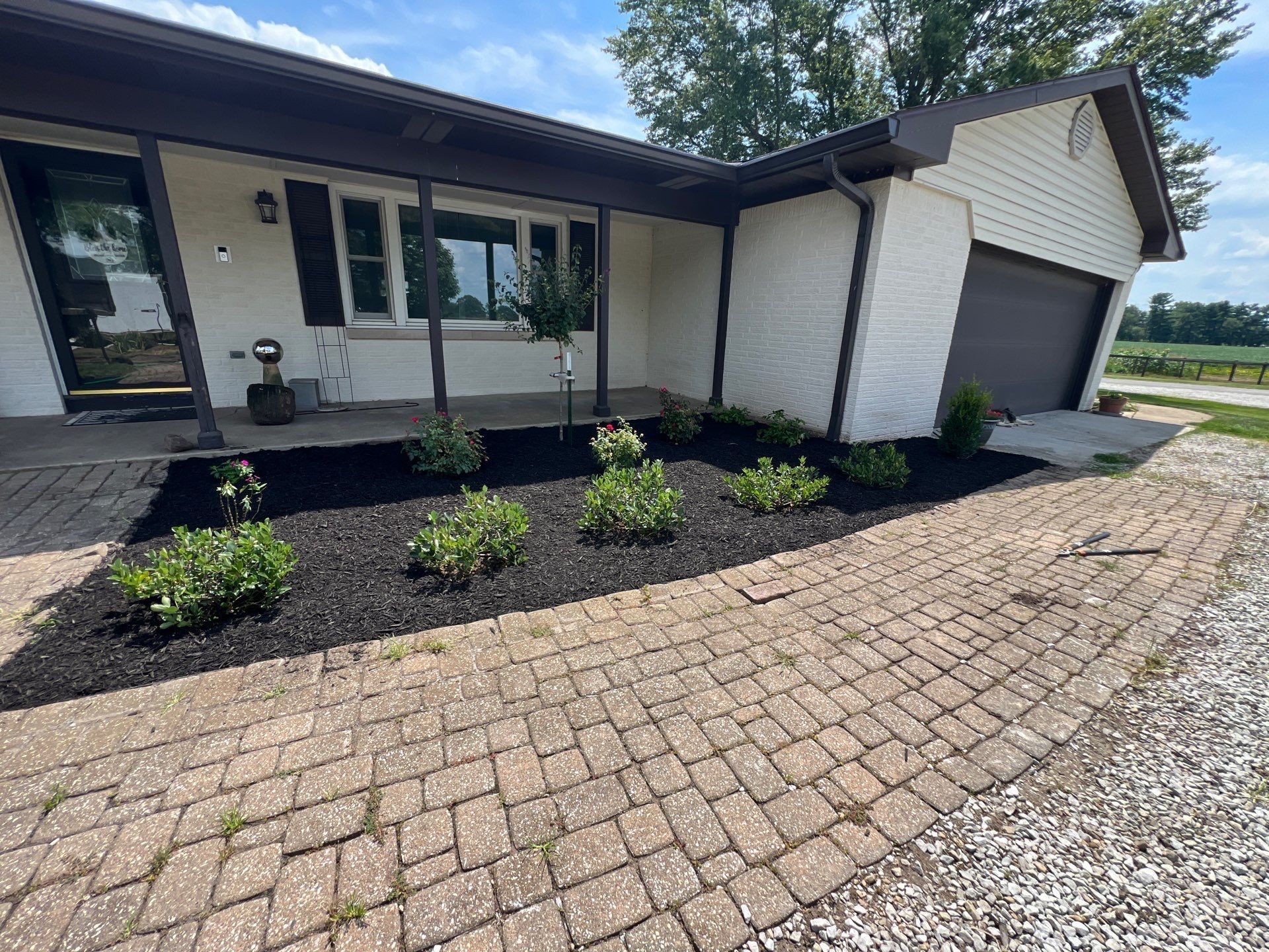 A white house with a garage and a brick driveway in front of it.