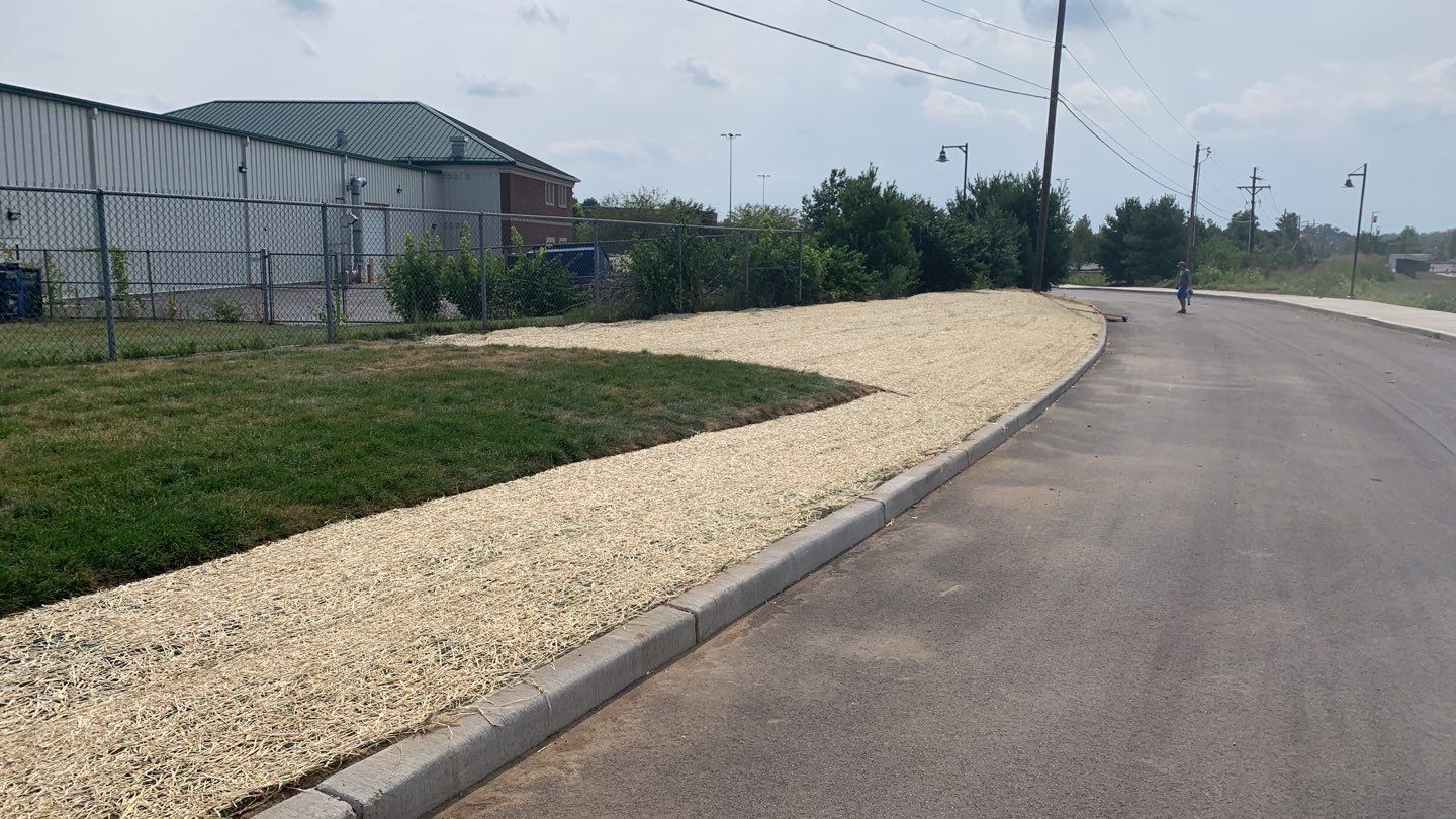 A road with gravel on the side of it and a building in the background.