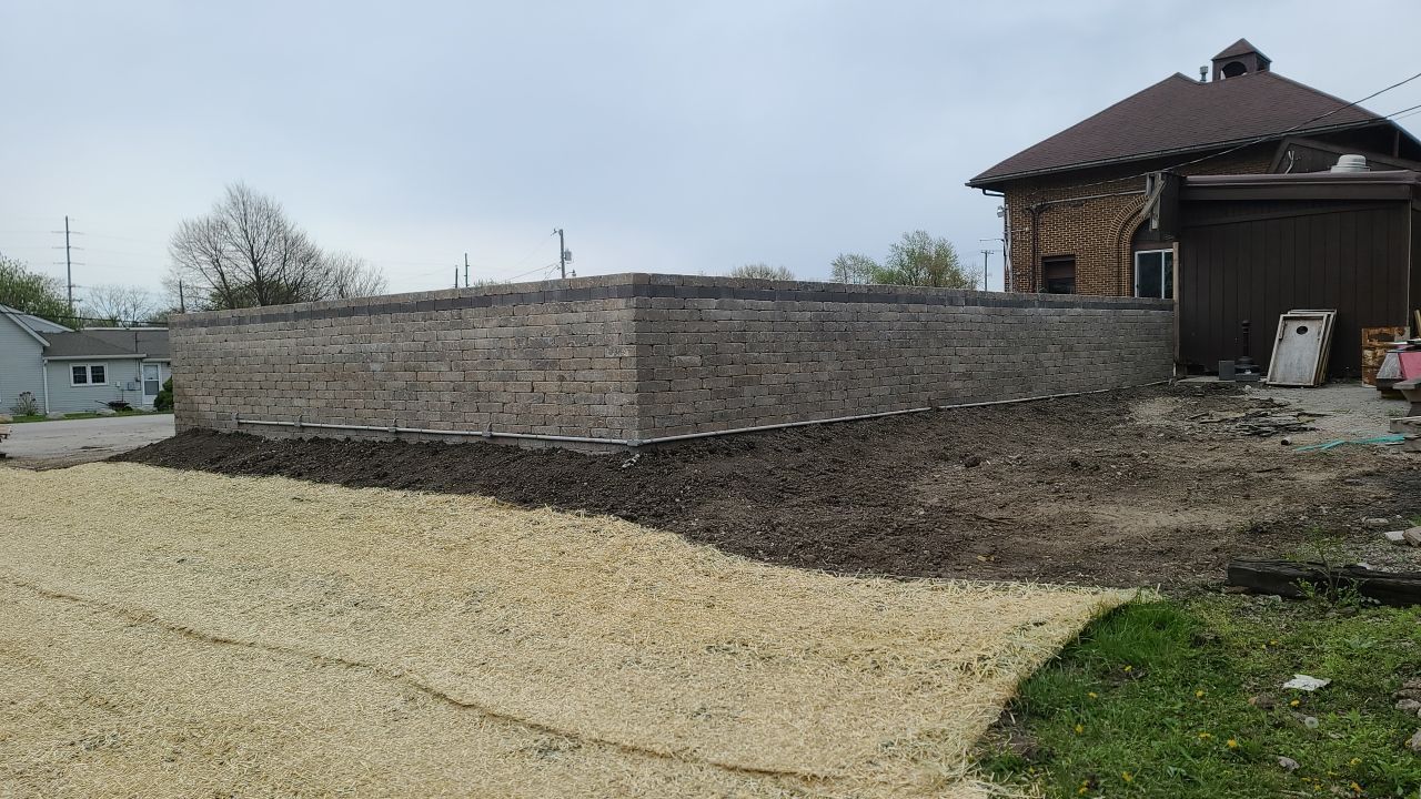 A large stone wall is being built in front of a house.