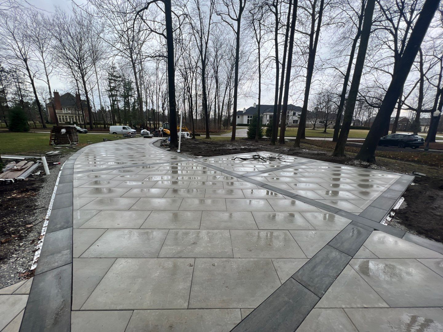 A concrete patio with trees in the background and a house in the background.