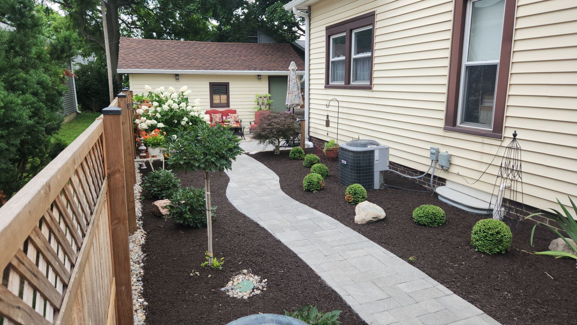 A walkway leading to a house with a wooden fence