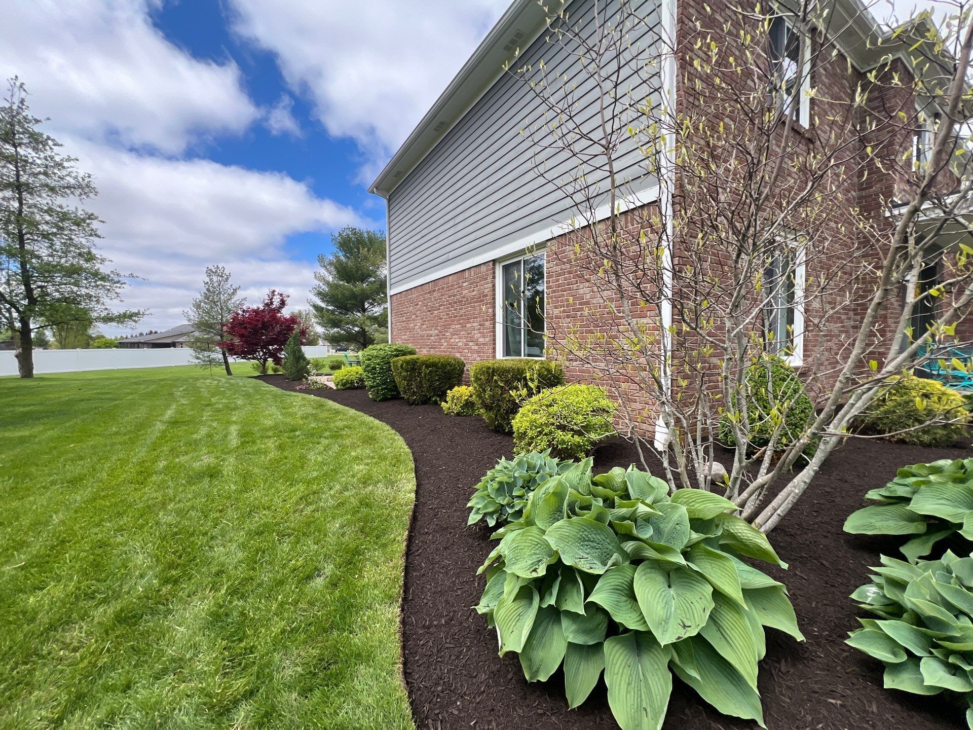 A large brick house with a lush green lawn in front of it.