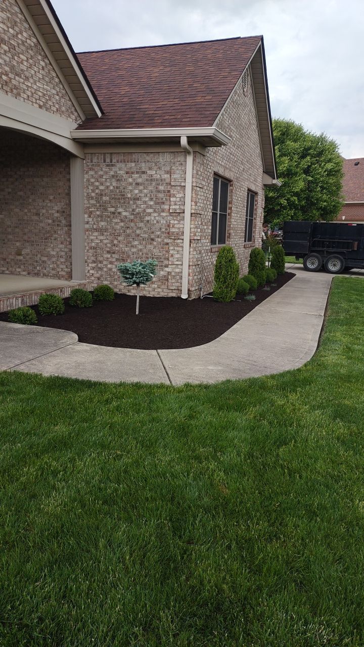 A brick house with a lush green lawn and a sidewalk in front of it.