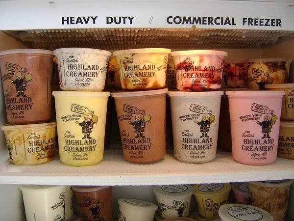 A commercial freezer filled with assorted pints of Highland Creamery ice cream on white wire shelves.