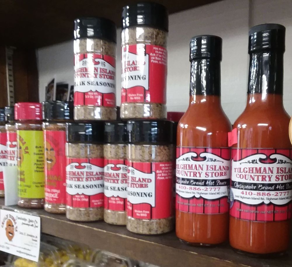 Bottles of Tilghman Island Country Store seasoning and hot sauce arranged on a shelf.