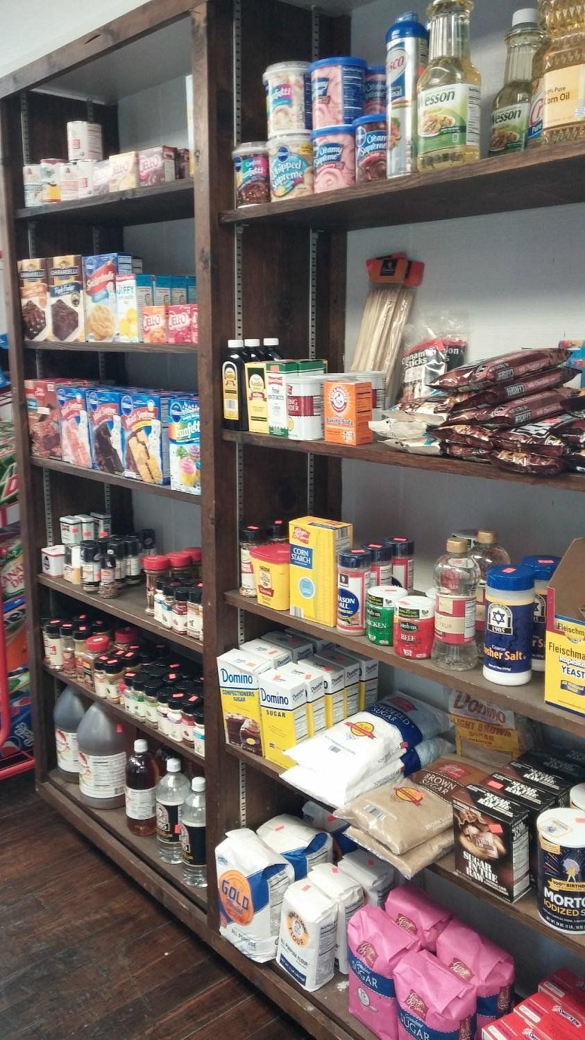Two wooden shelving units filled with various food products, including boxes, jars, and bags of pantry staples.