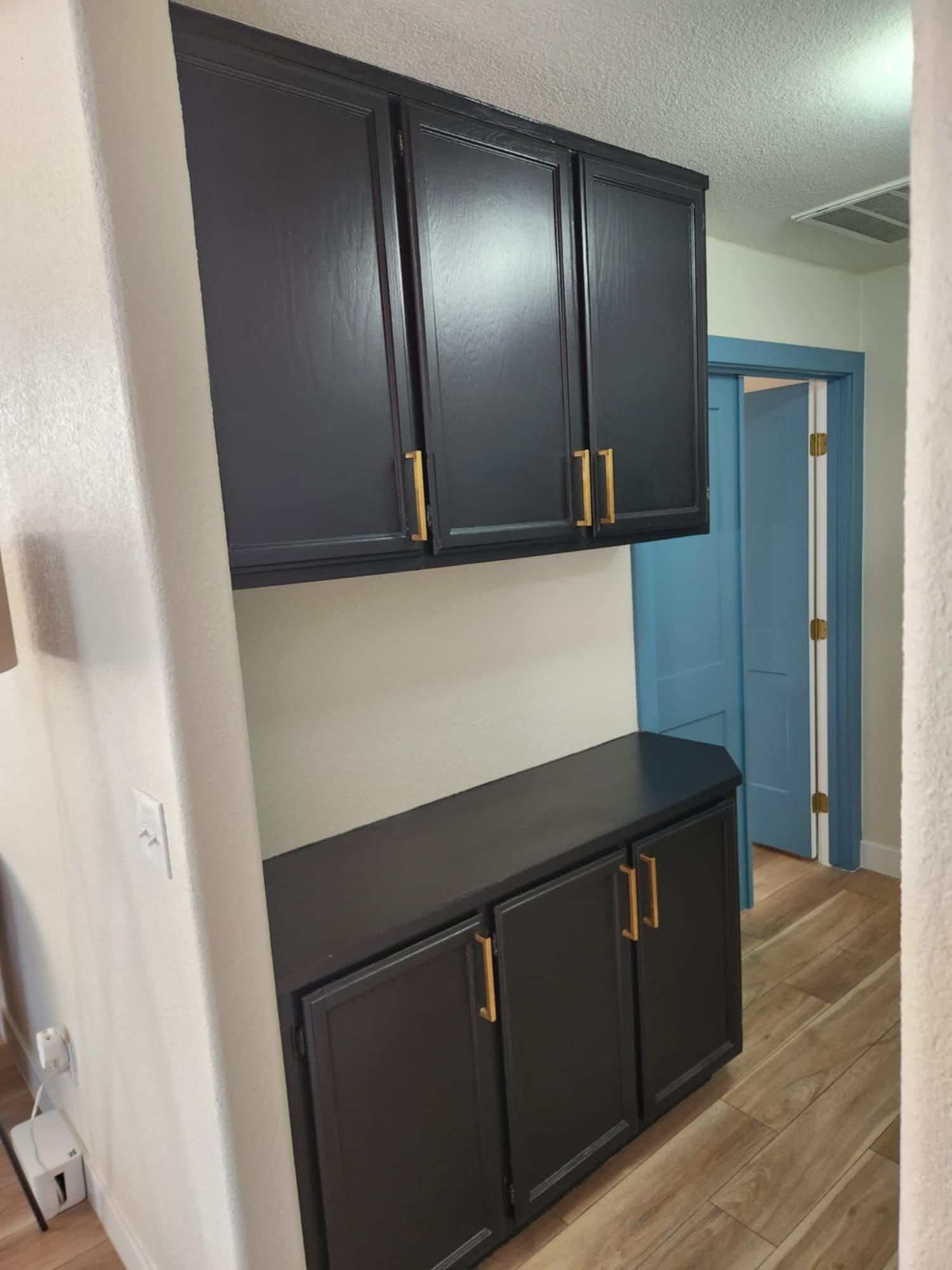 A kitchen with black cabinets and a blue door