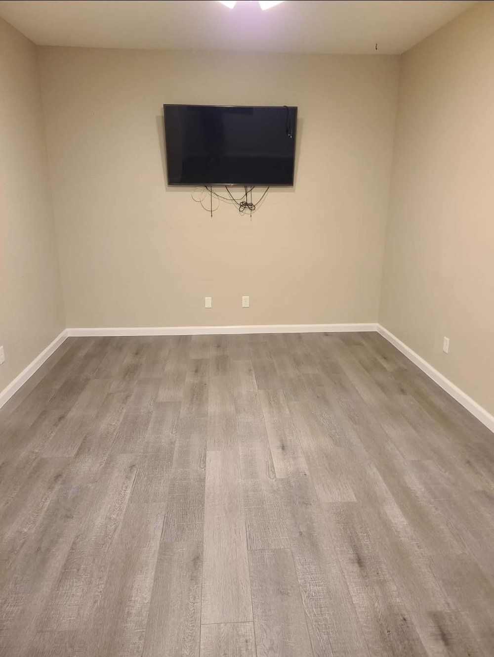 A large empty room with a flat screen tv on the wall.