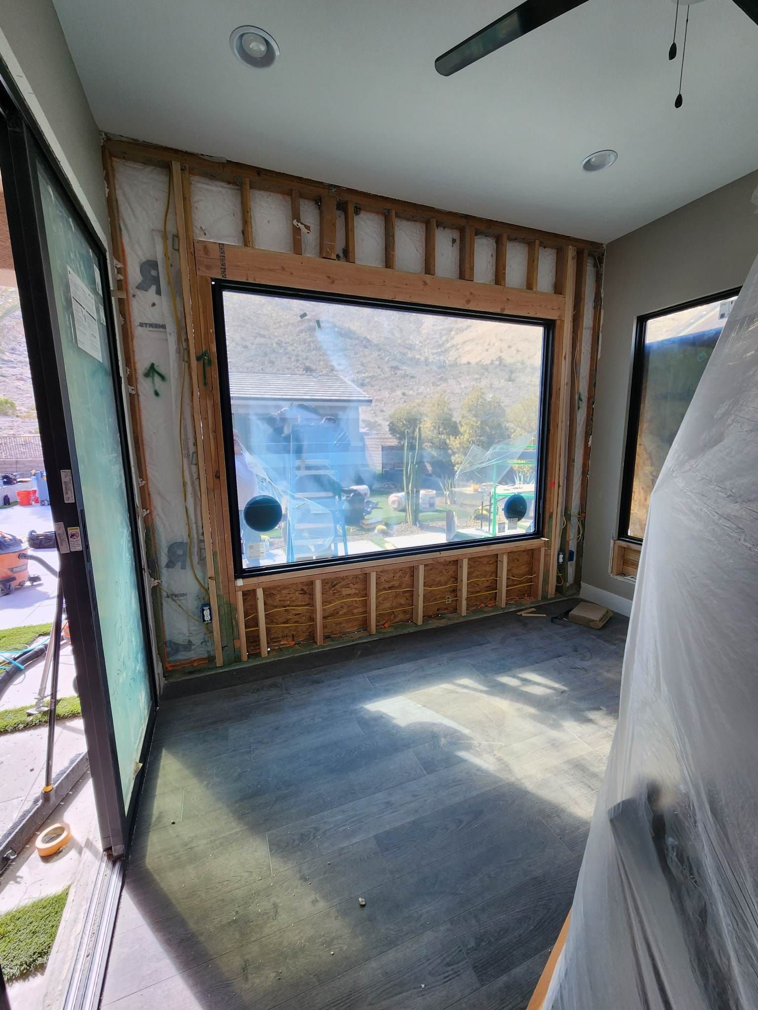 A room with a large window and a ceiling fan.