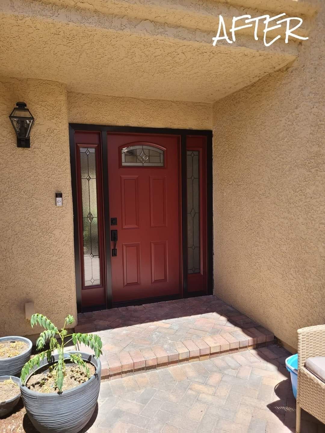 A picture of a house with a red door and potted plants in front of it.