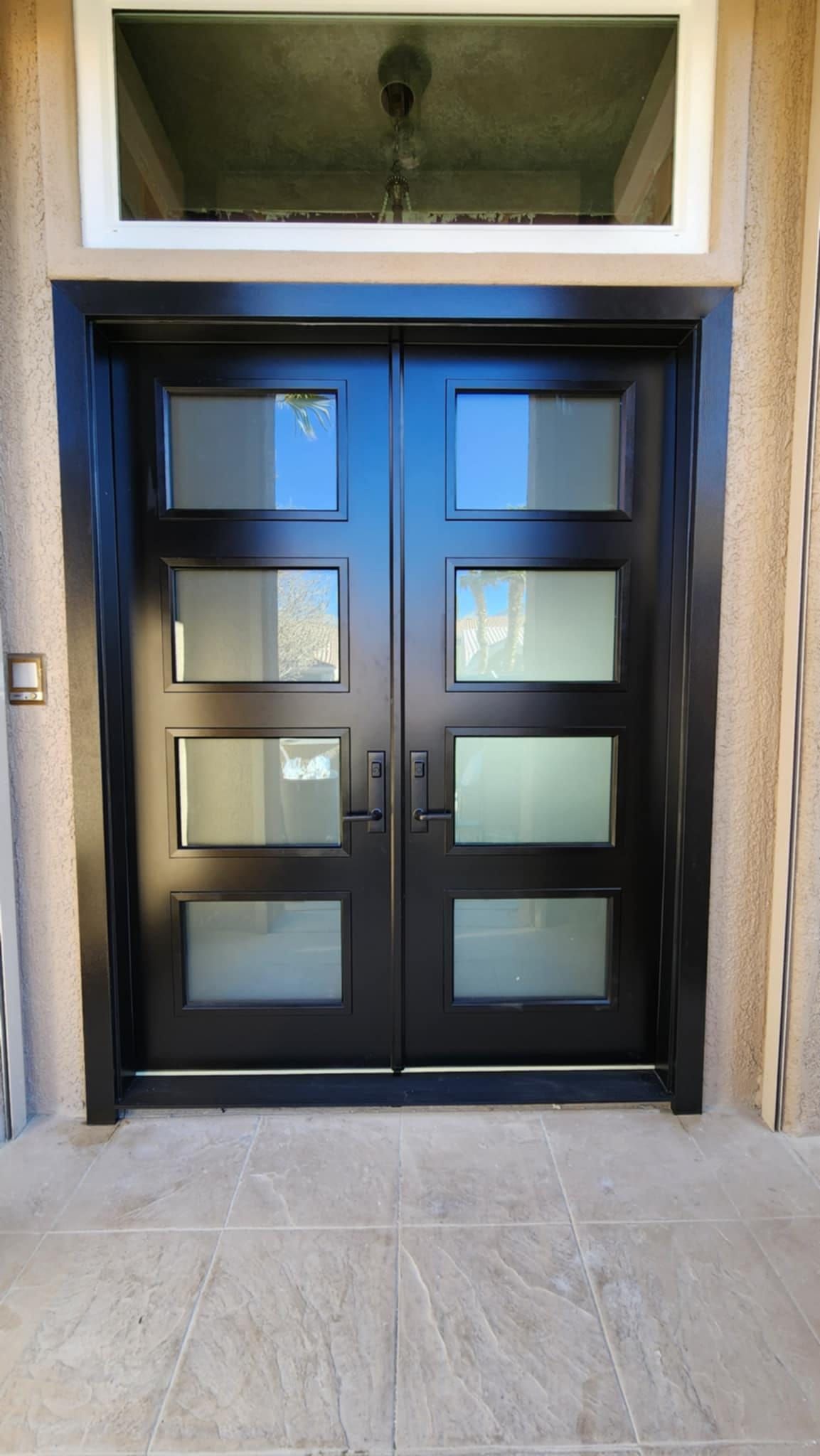 A black double door with a window above it.