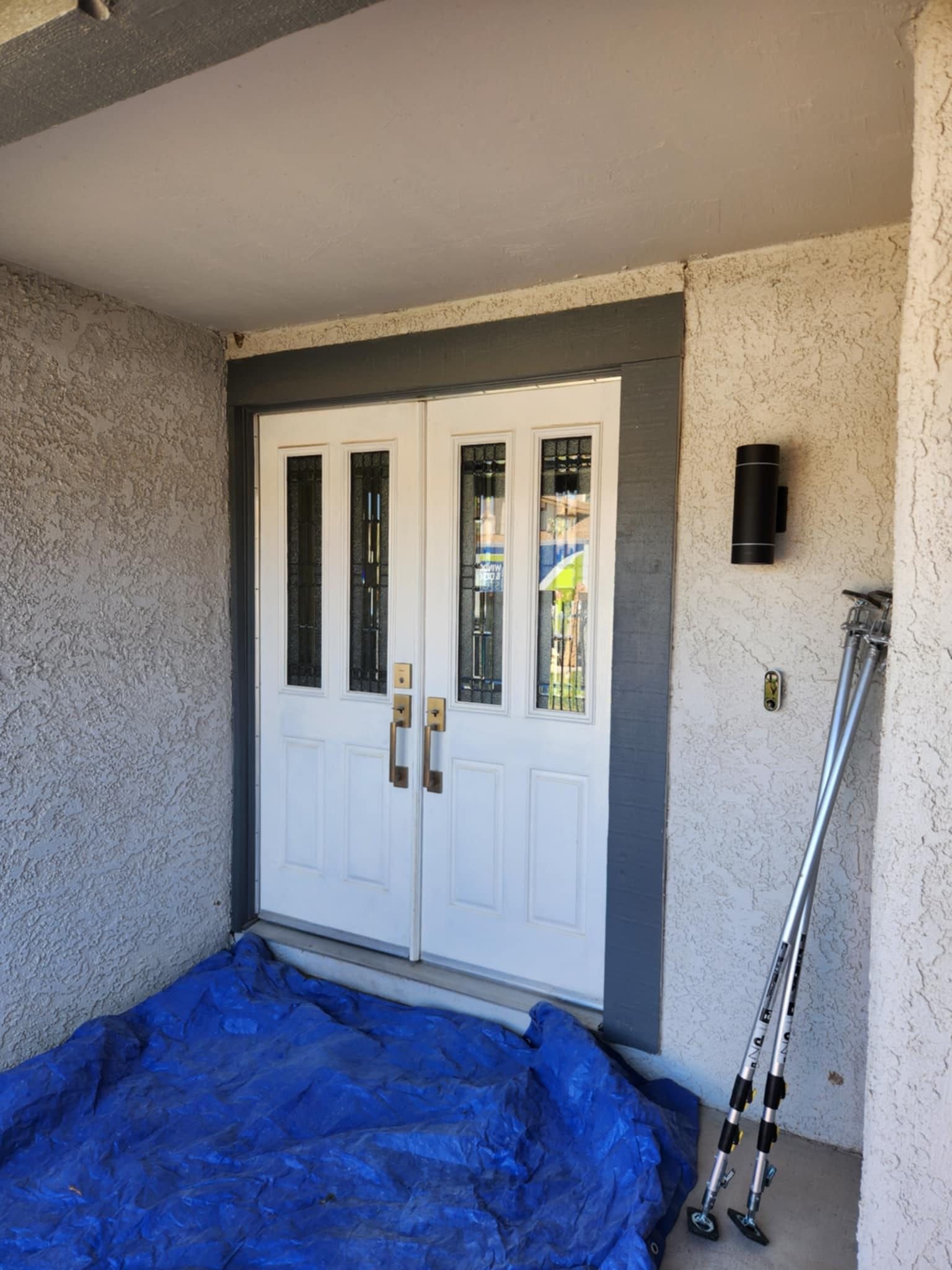 A white door with a blue tarp on the ground in front of it.