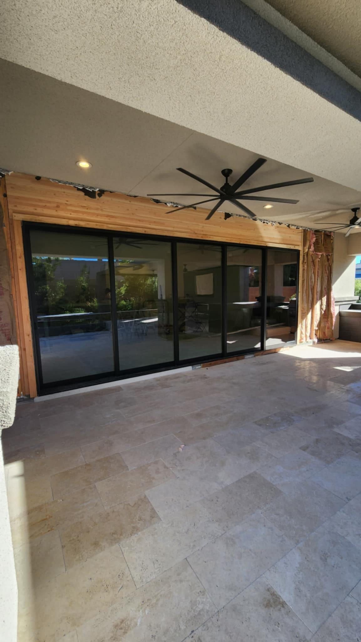 A large patio with sliding glass doors and a ceiling fan.