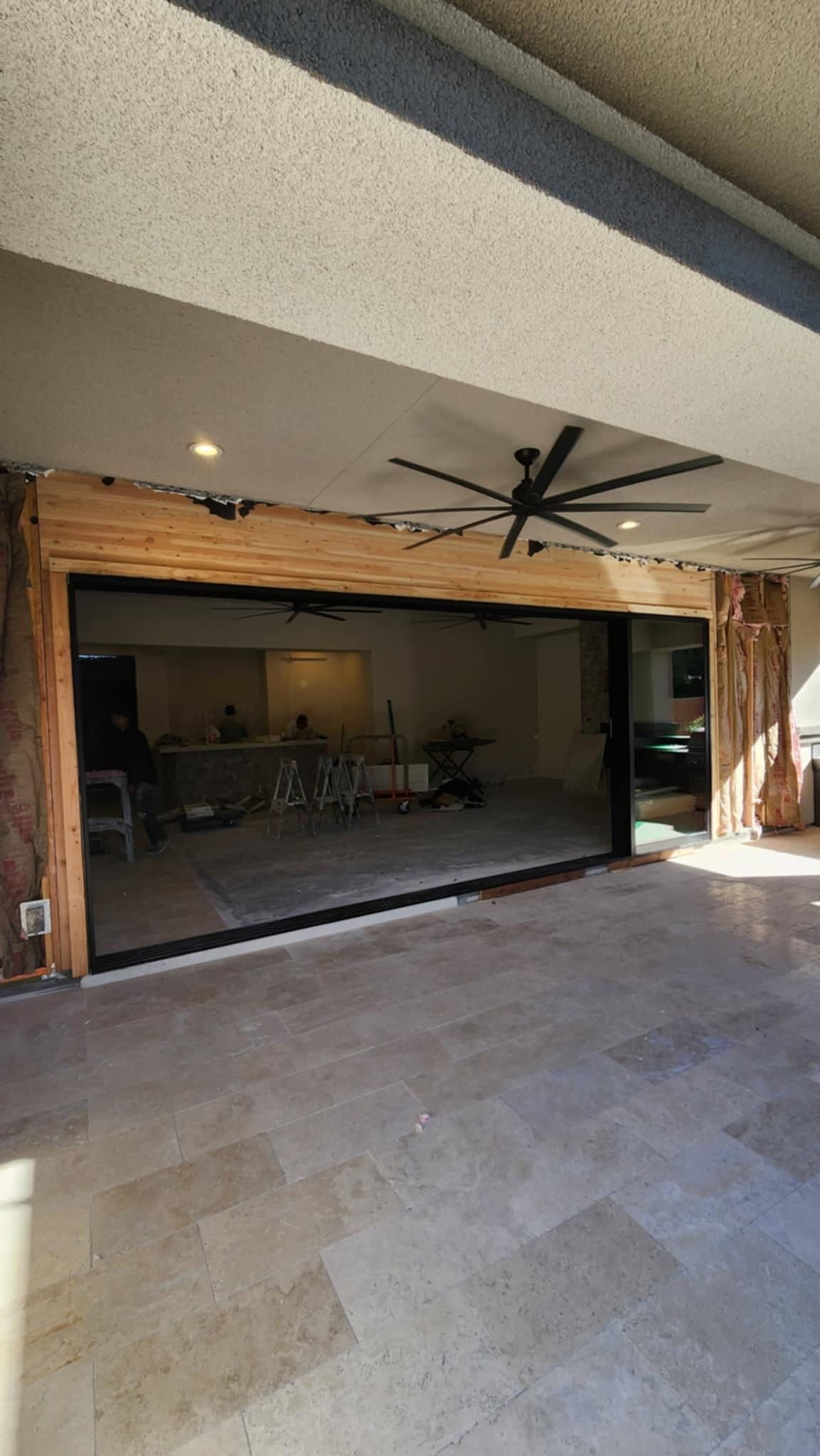 A large sliding glass door is open to a patio with a ceiling fan.