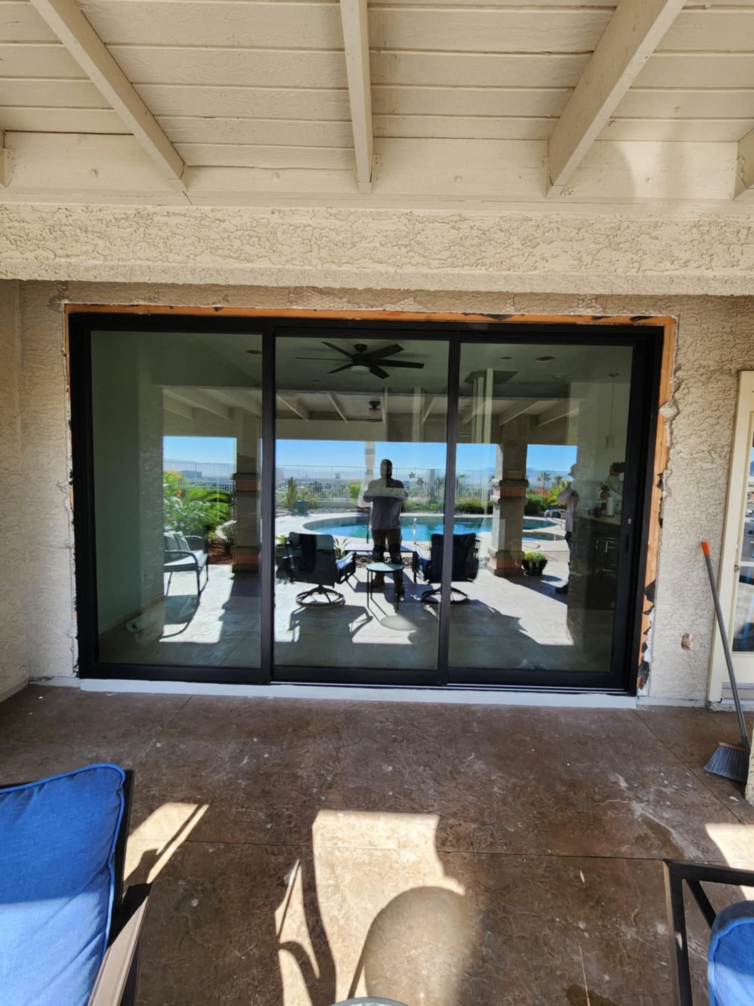 A man is standing in front of a large sliding glass door.