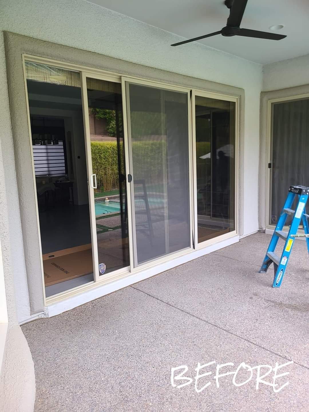A before picture of a patio with sliding glass doors and a ladder.