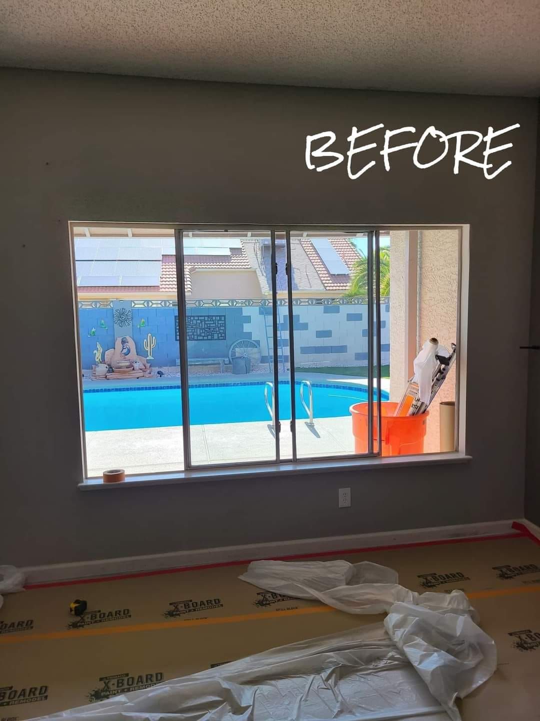 A before picture of a room with a window overlooking a pool.
